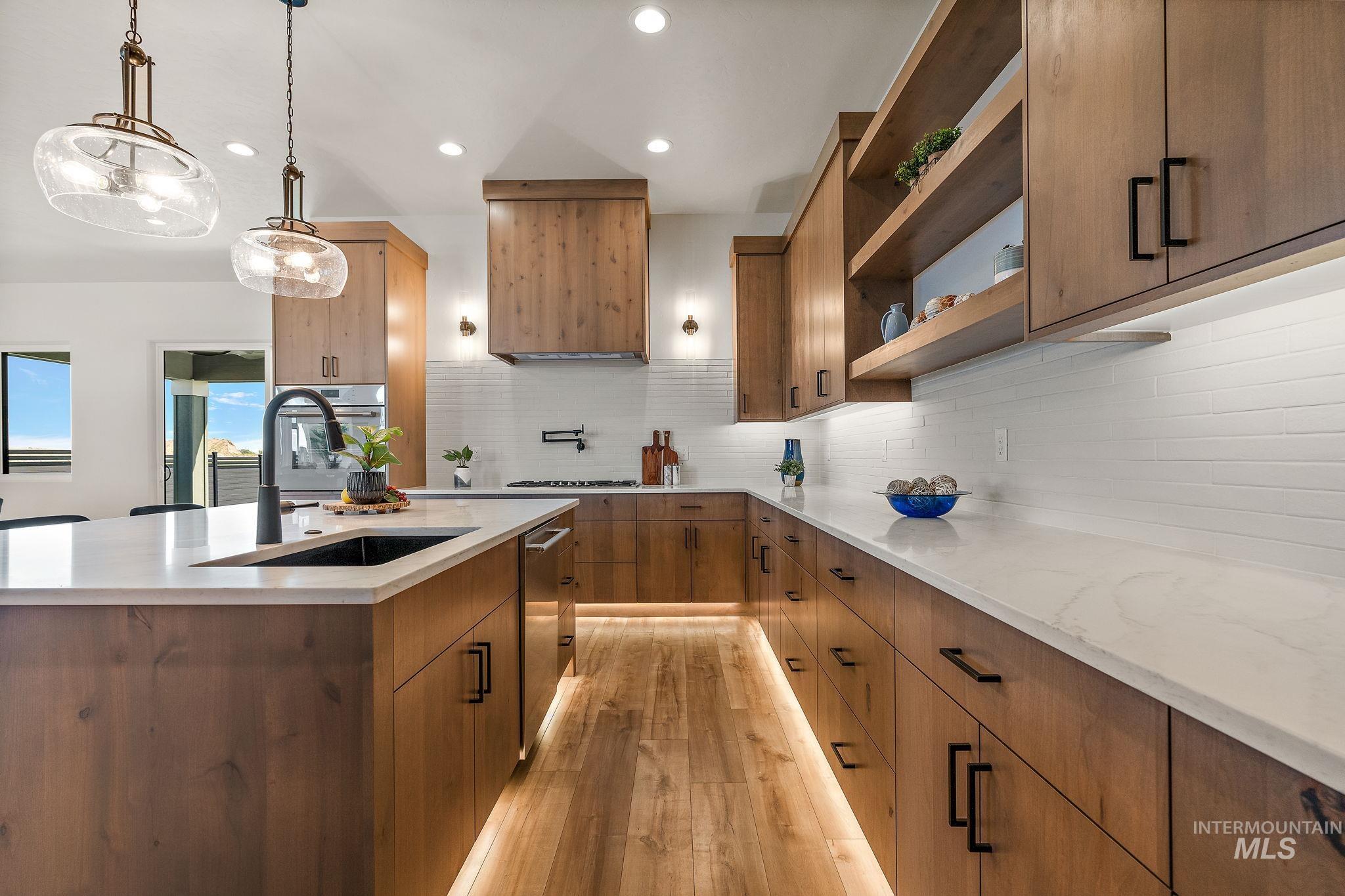 Kitchen with light stone counters, decorative backsplash, hanging light fixtures, open shelves, and recessed lighting