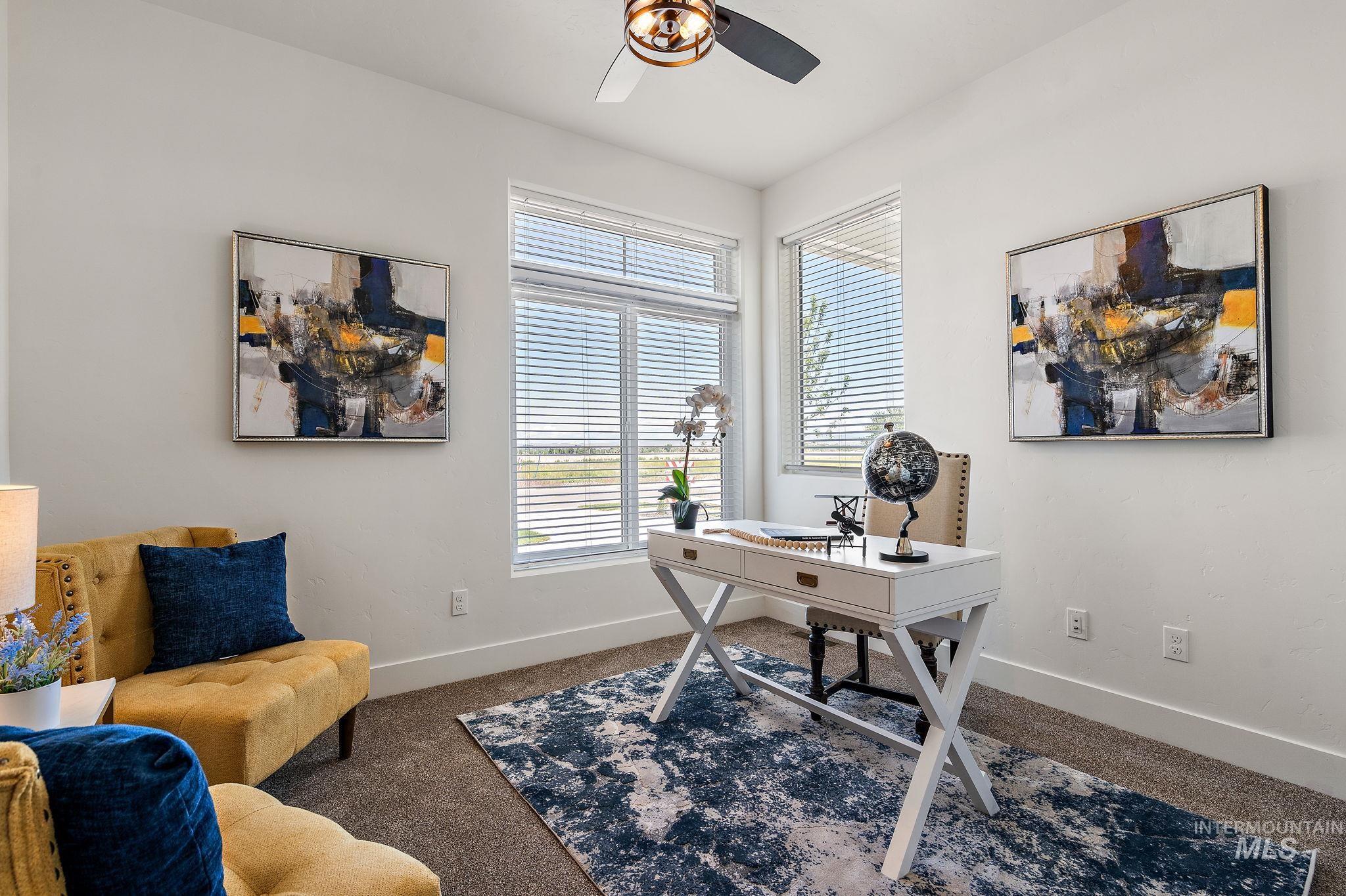 Carpeted office with baseboards and a ceiling fan