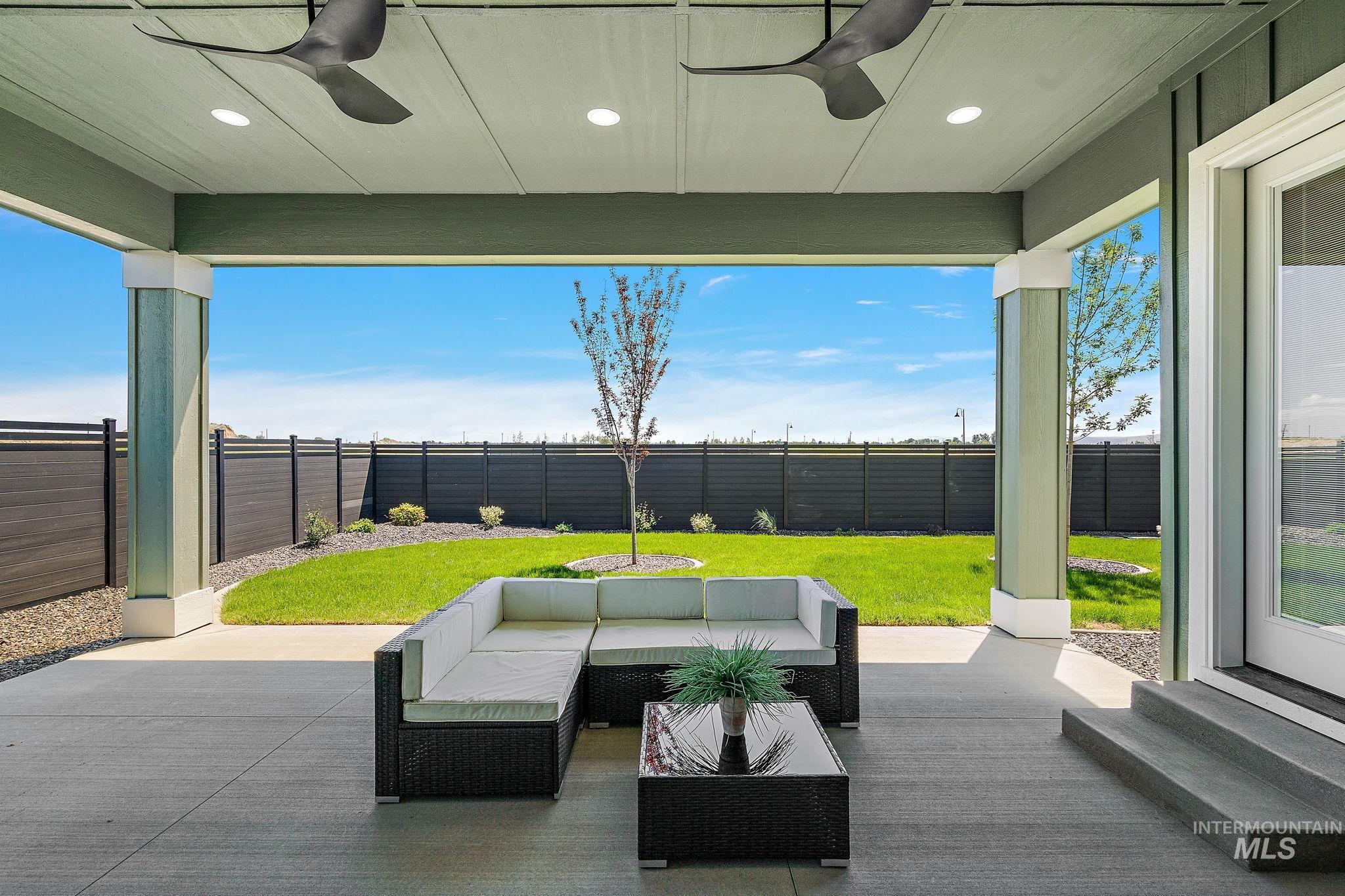Fenced backyard featuring a patio, ceiling fan, and an outdoor hangout area