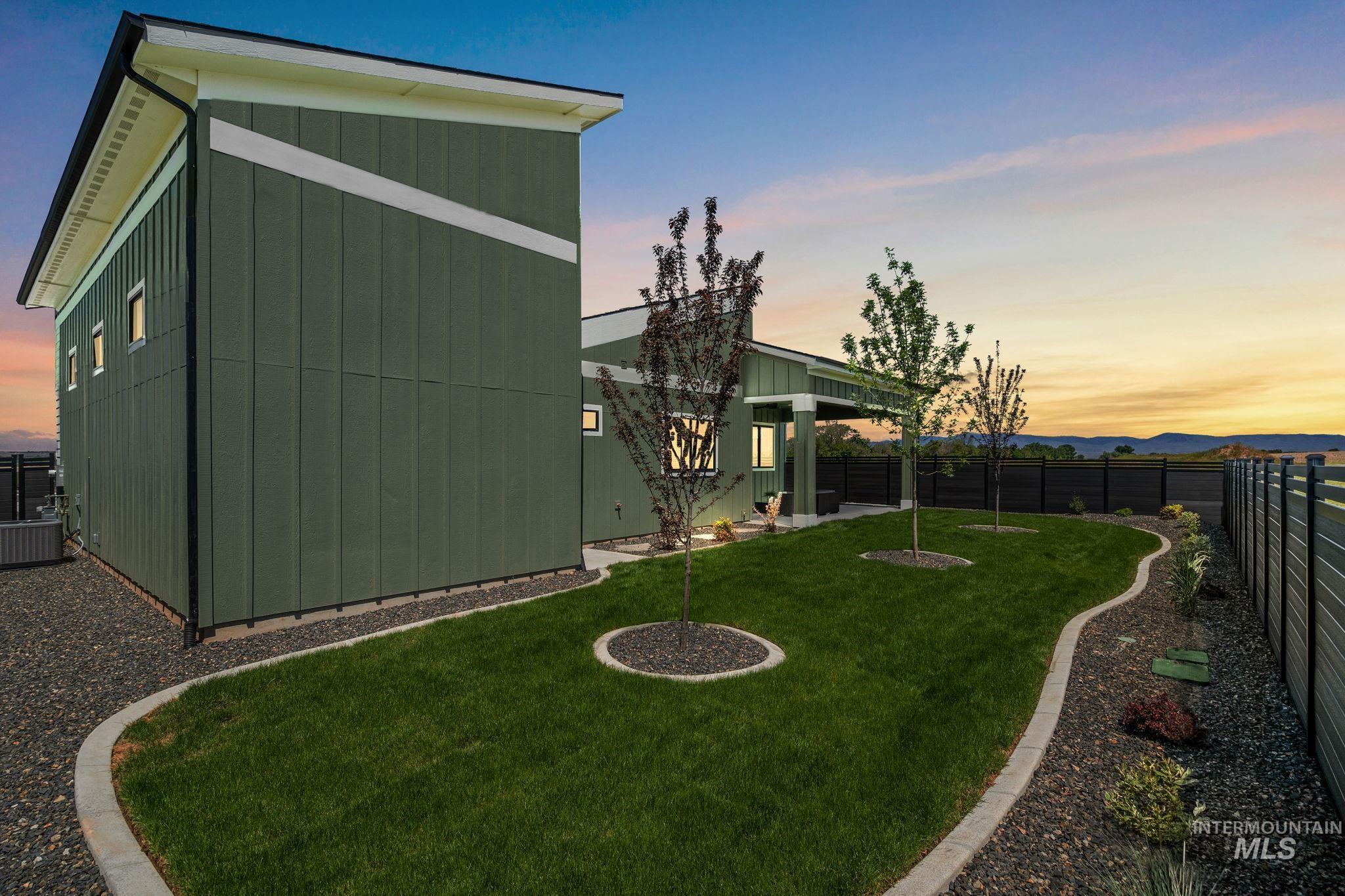 Yard at dusk with a fenced backyard, a patio, and a mountain view