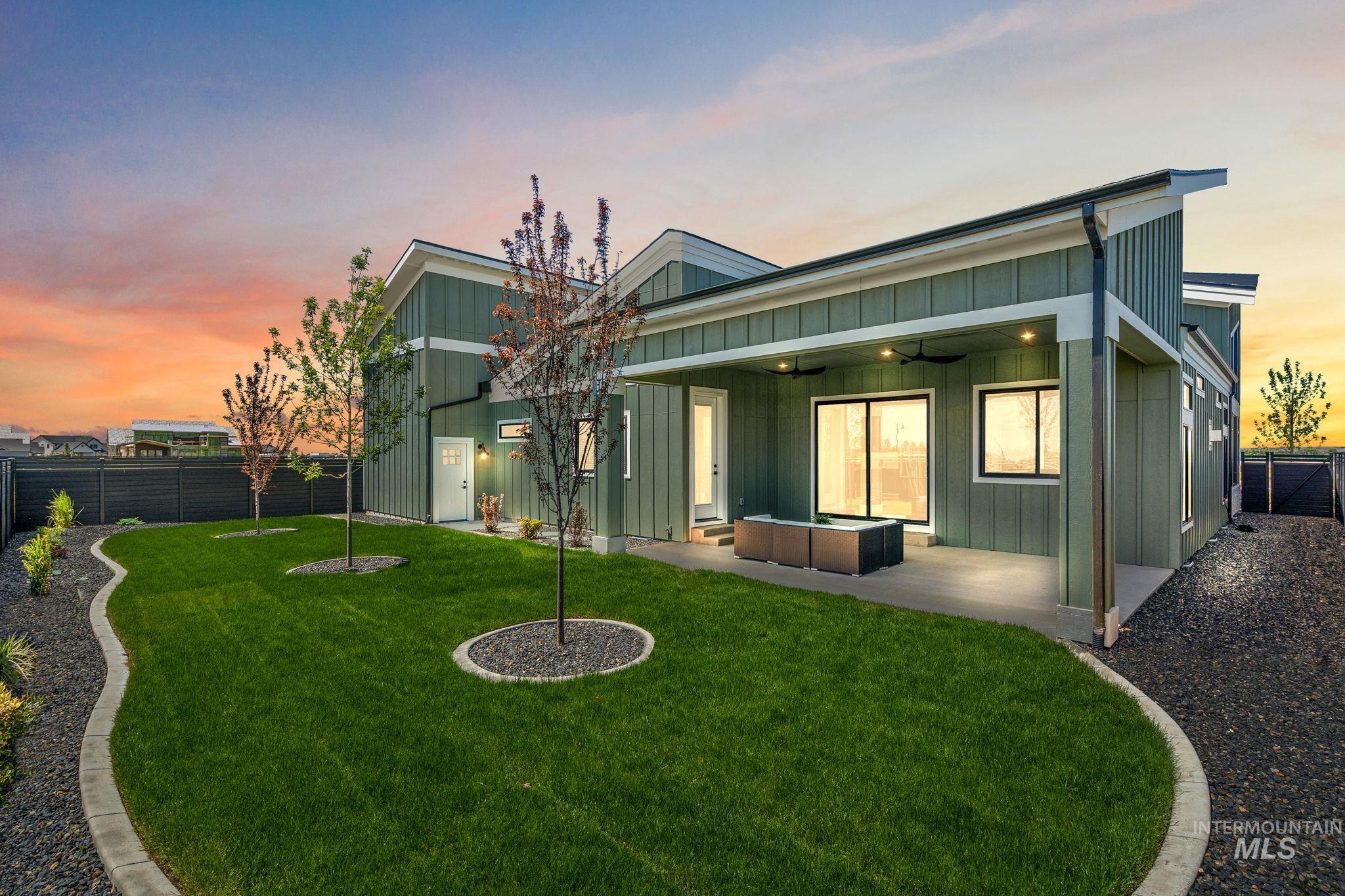 Back of property at dusk with board and batten siding, a fenced backyard, a ceiling fan, a patio, and an outdoor hangout area