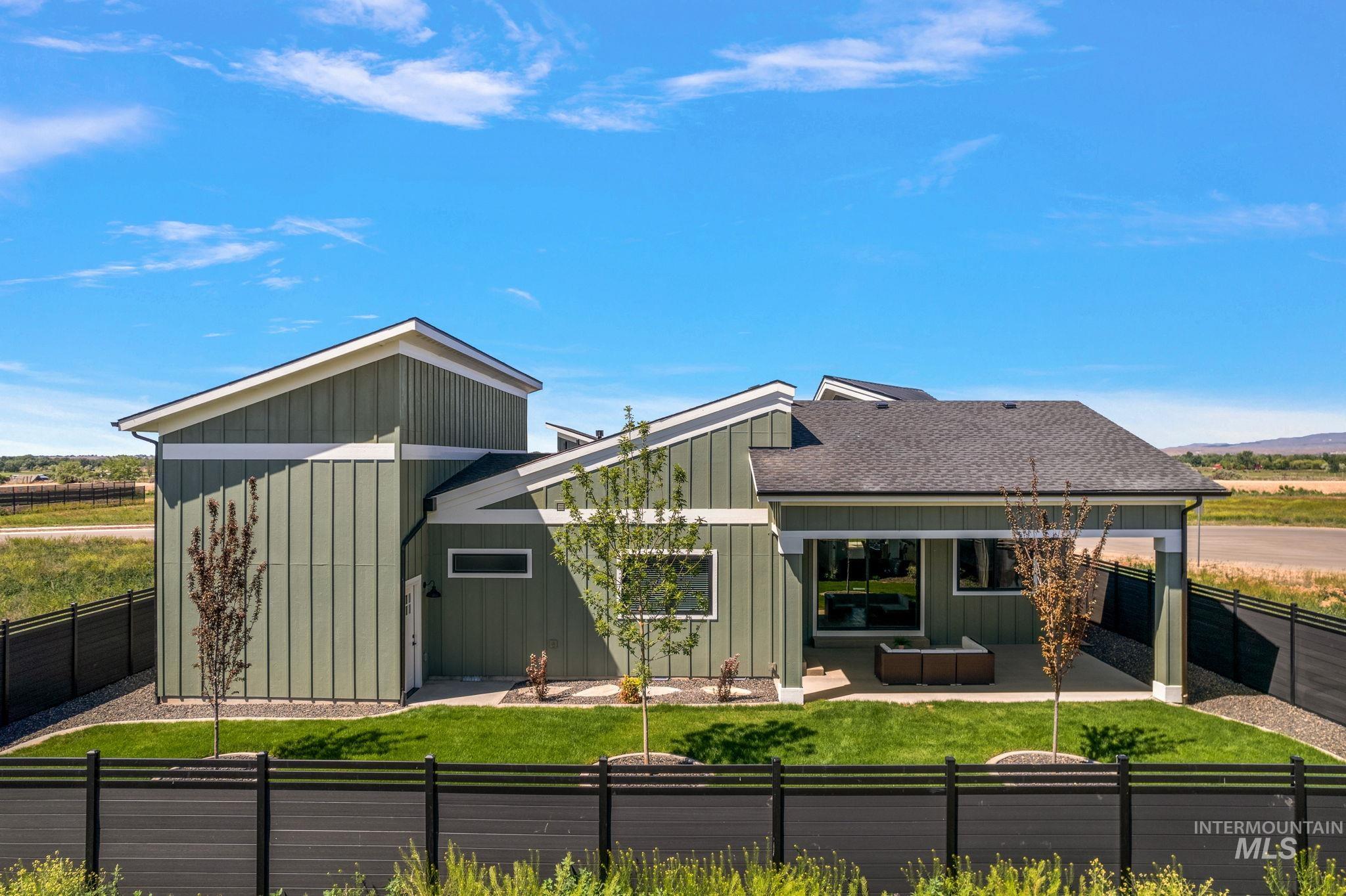Back of property with board and batten siding, a fenced backyard, a patio area, and a shingled roof