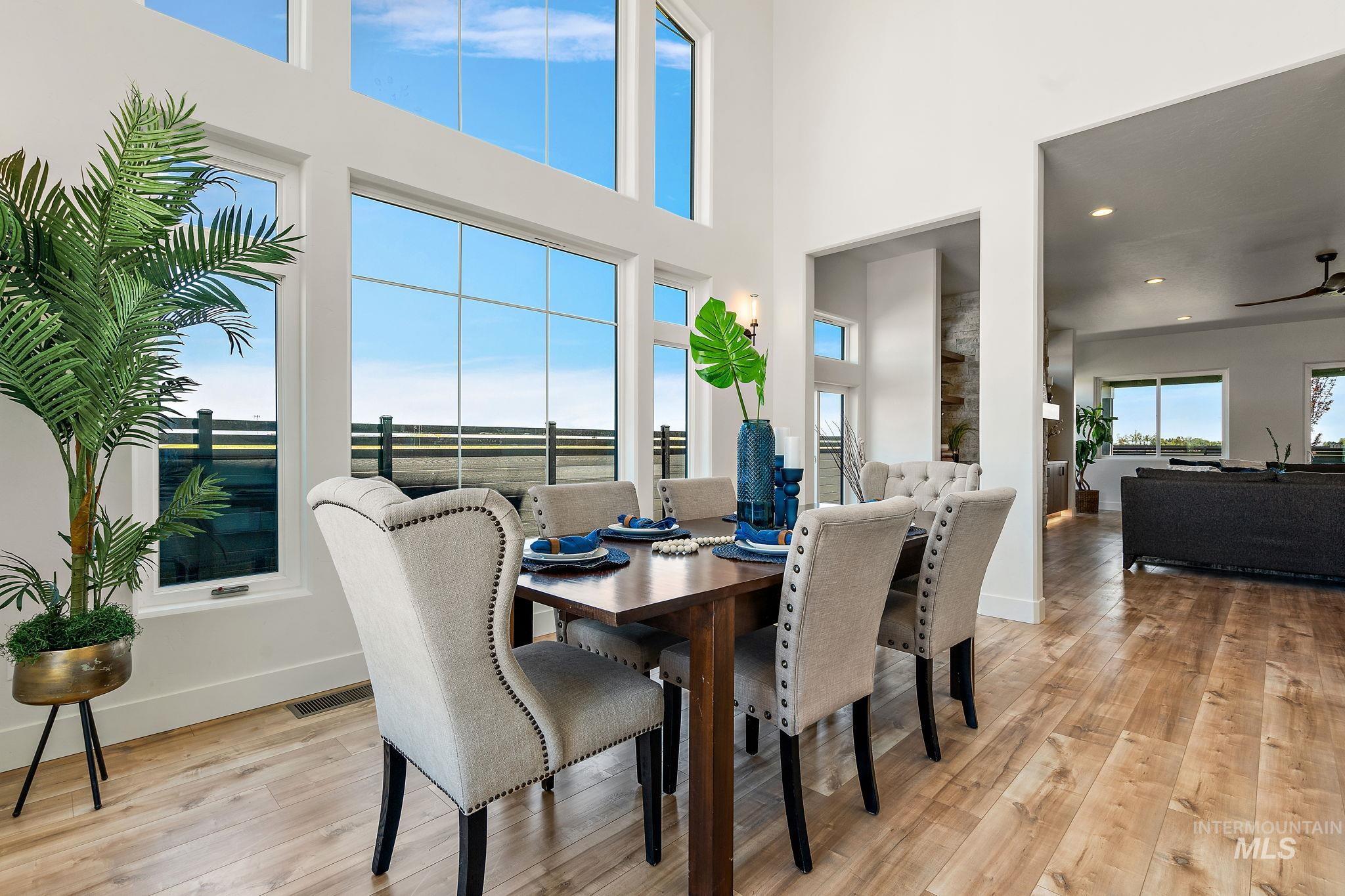 Dining room with a towering ceiling, light wood finished floors, ceiling fan, and recessed lighting