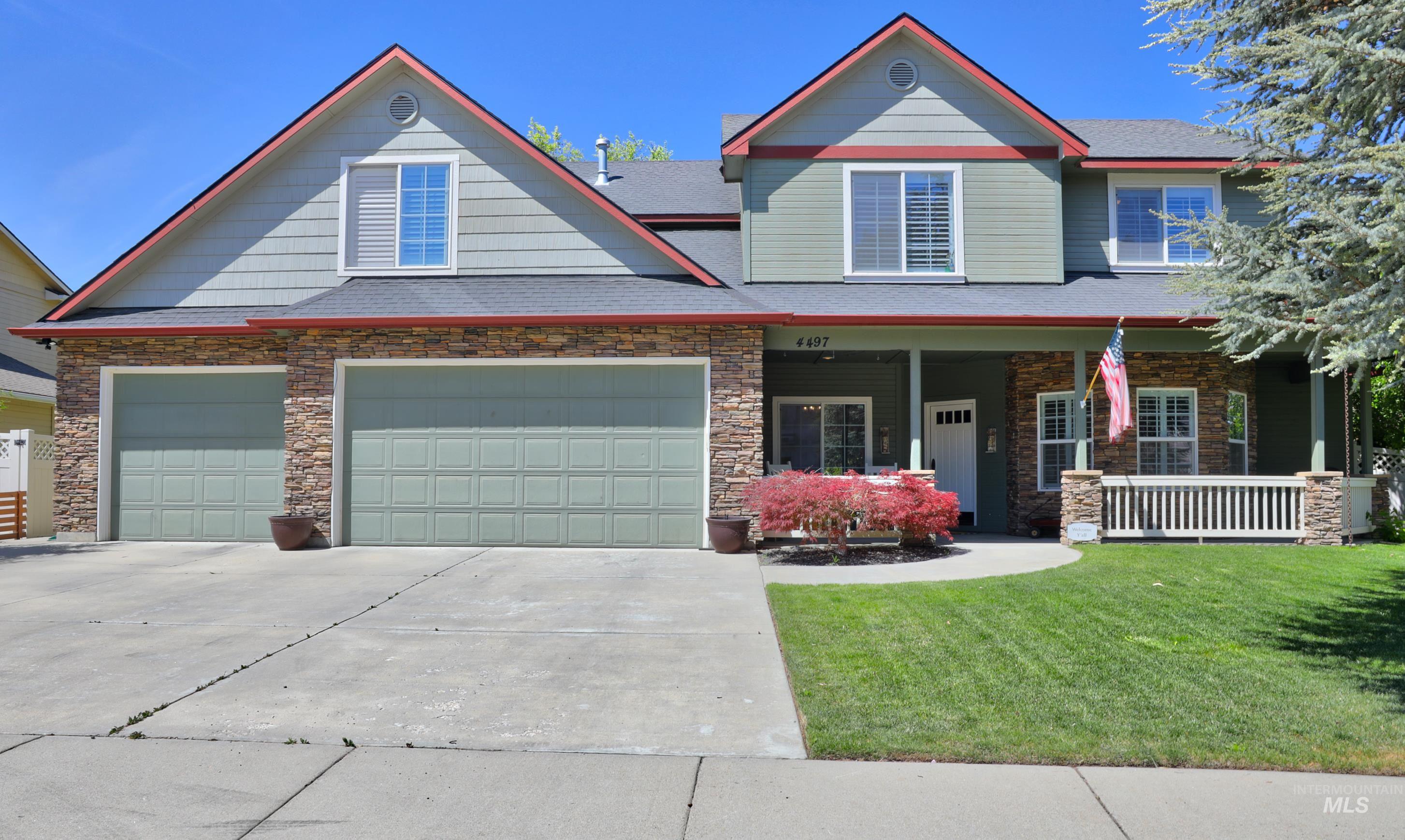 Craftsman inspired home featuring a porch, driveway, stone siding, and a front lawn