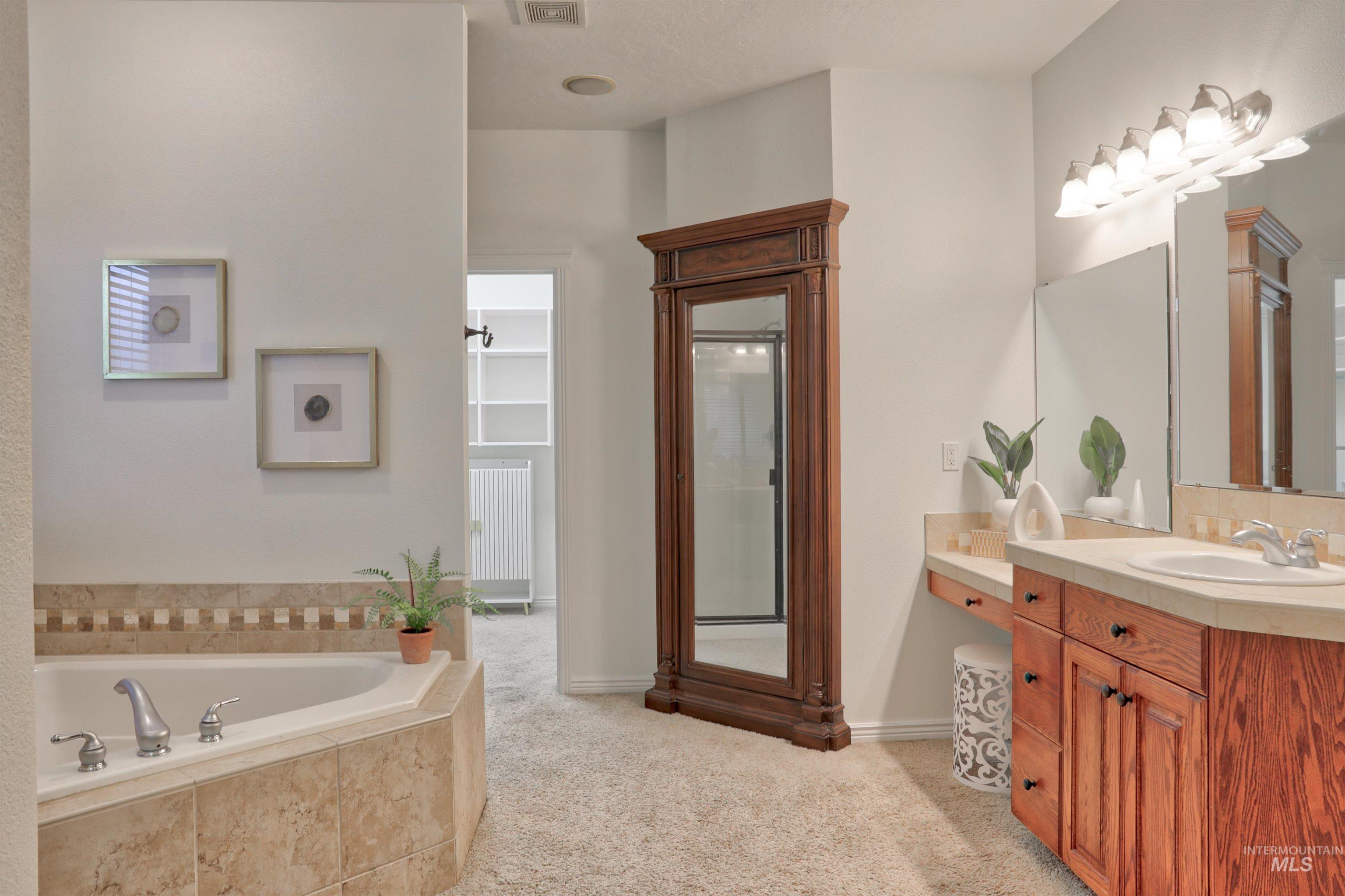 Bathroom featuring vanity, a garden tub, and a stall shower