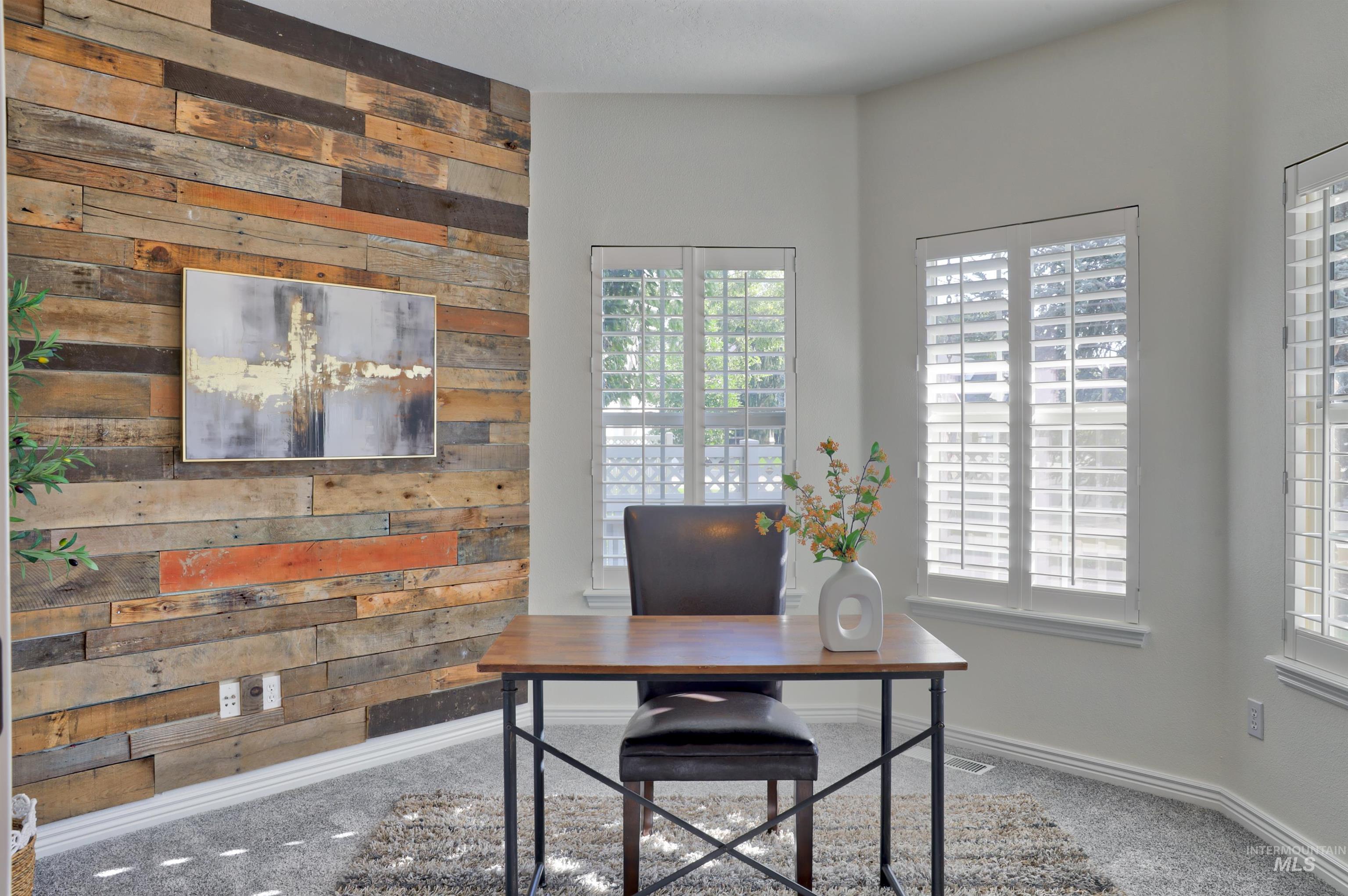 Carpeted home office featuring wood walls and baseboards