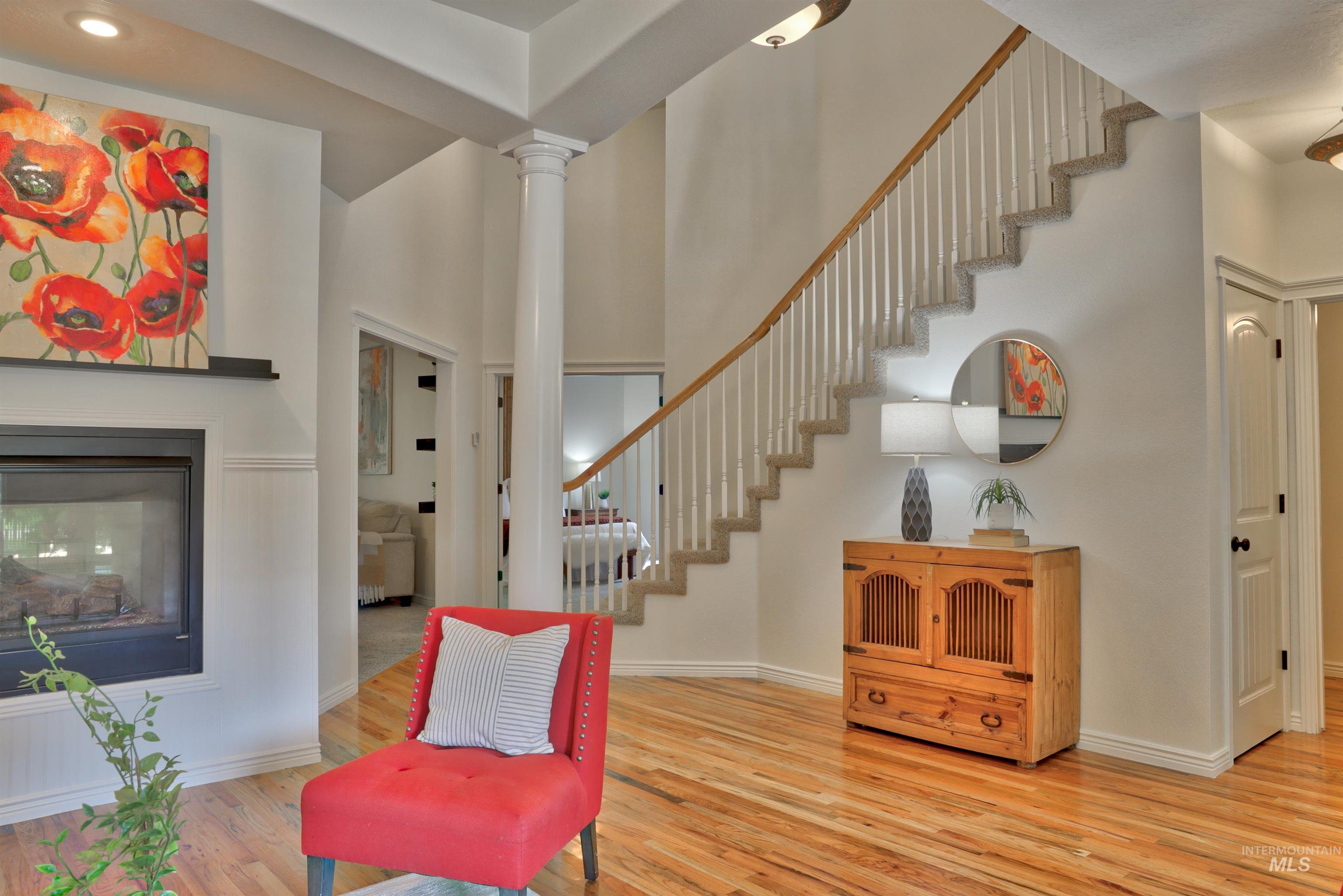 Sitting room featuring a towering ceiling, light wood finished floors, a multi sided fireplace, and stairway