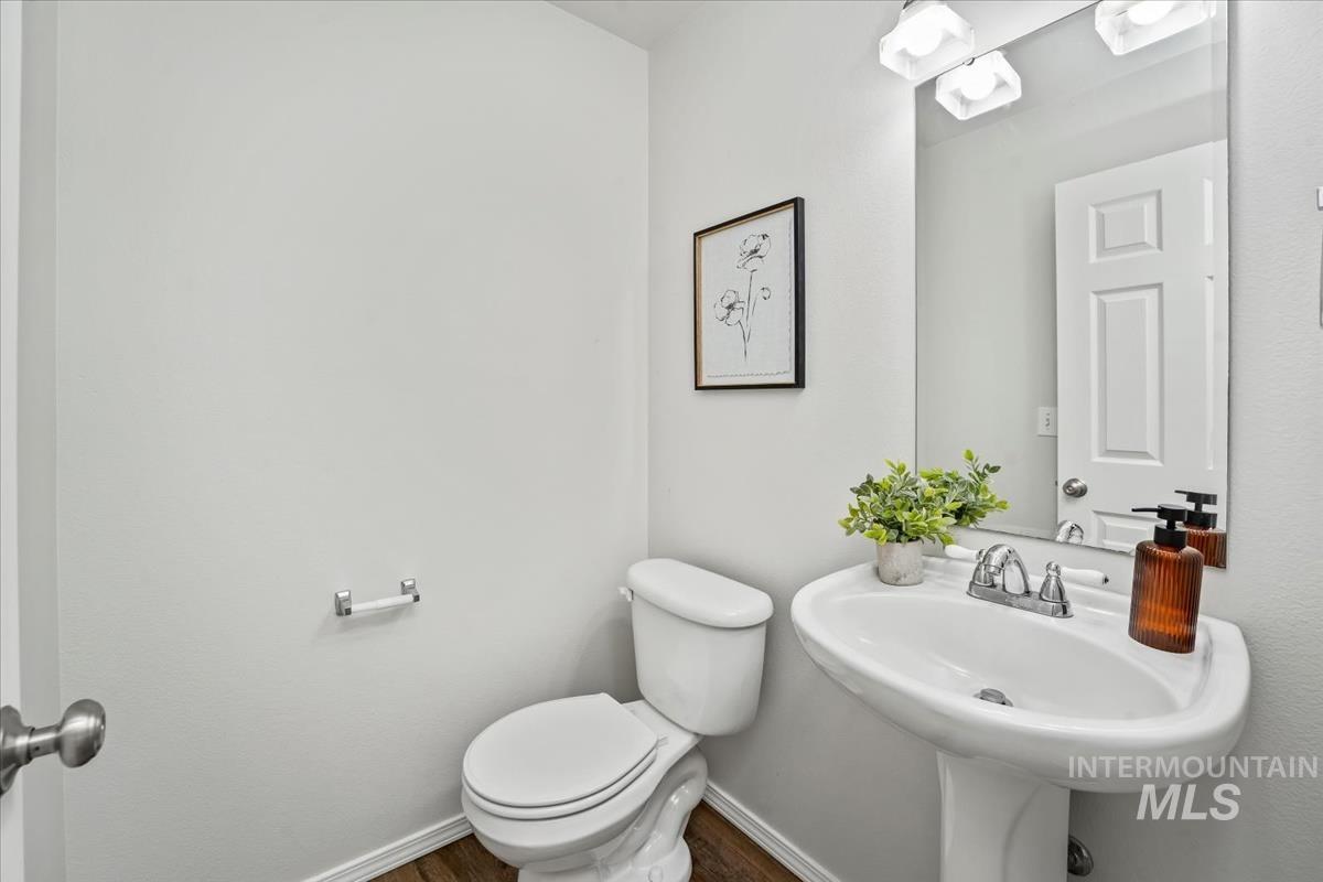 Half bath featuring toilet and dark wood-style flooring