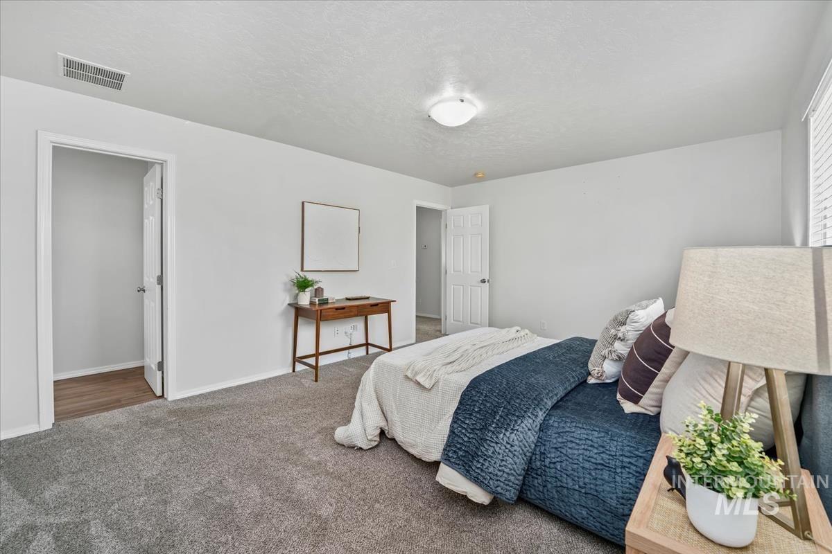 Carpeted bedroom featuring a textured ceiling and baseboards