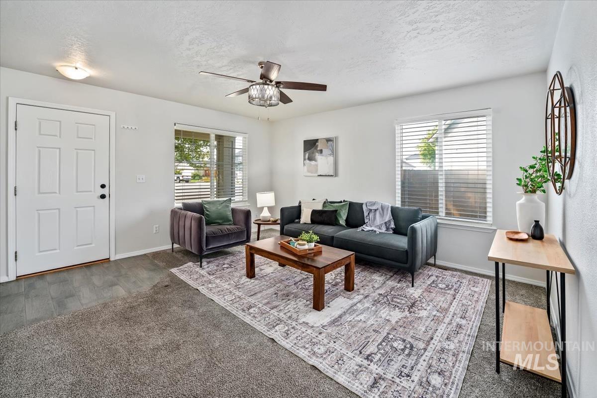 Carpeted living area featuring ceiling fan and a textured ceiling