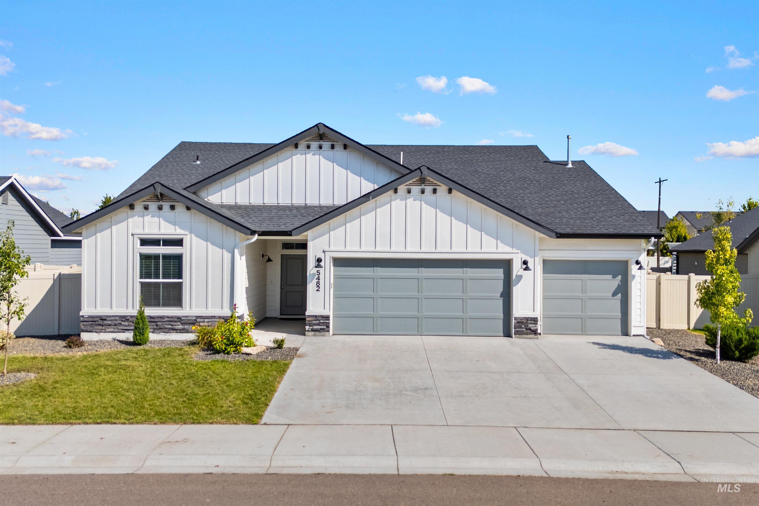 Modern inspired farmhouse with board and batten siding, a shingled roof, stone siding, a garage, and driveway