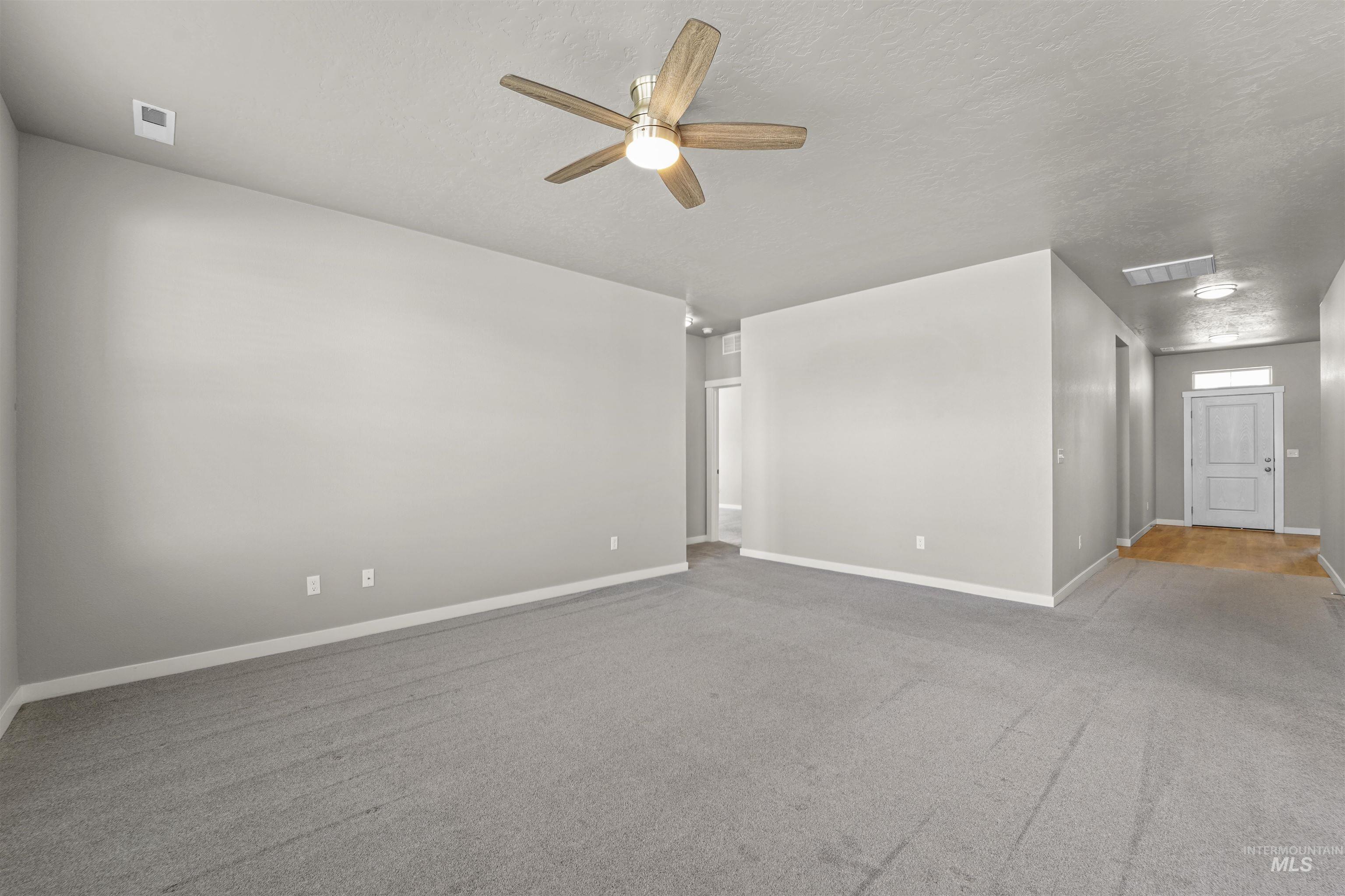 Spare room featuring light carpet, a textured ceiling, and ceiling fan