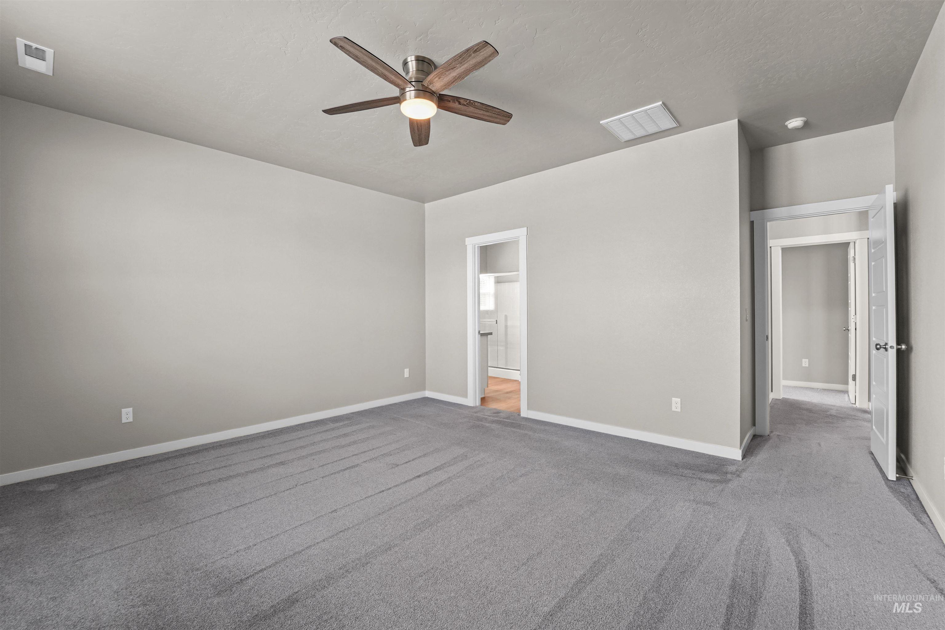 Unfurnished bedroom with ceiling fan, light carpet, and connected bathroom