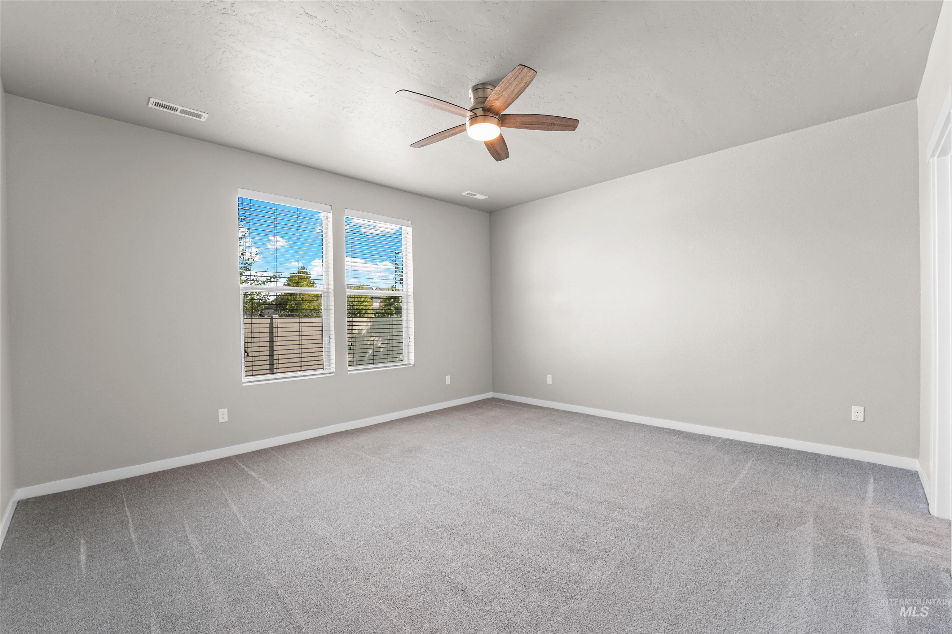 Spare room featuring light carpet, ceiling fan, and a textured ceiling