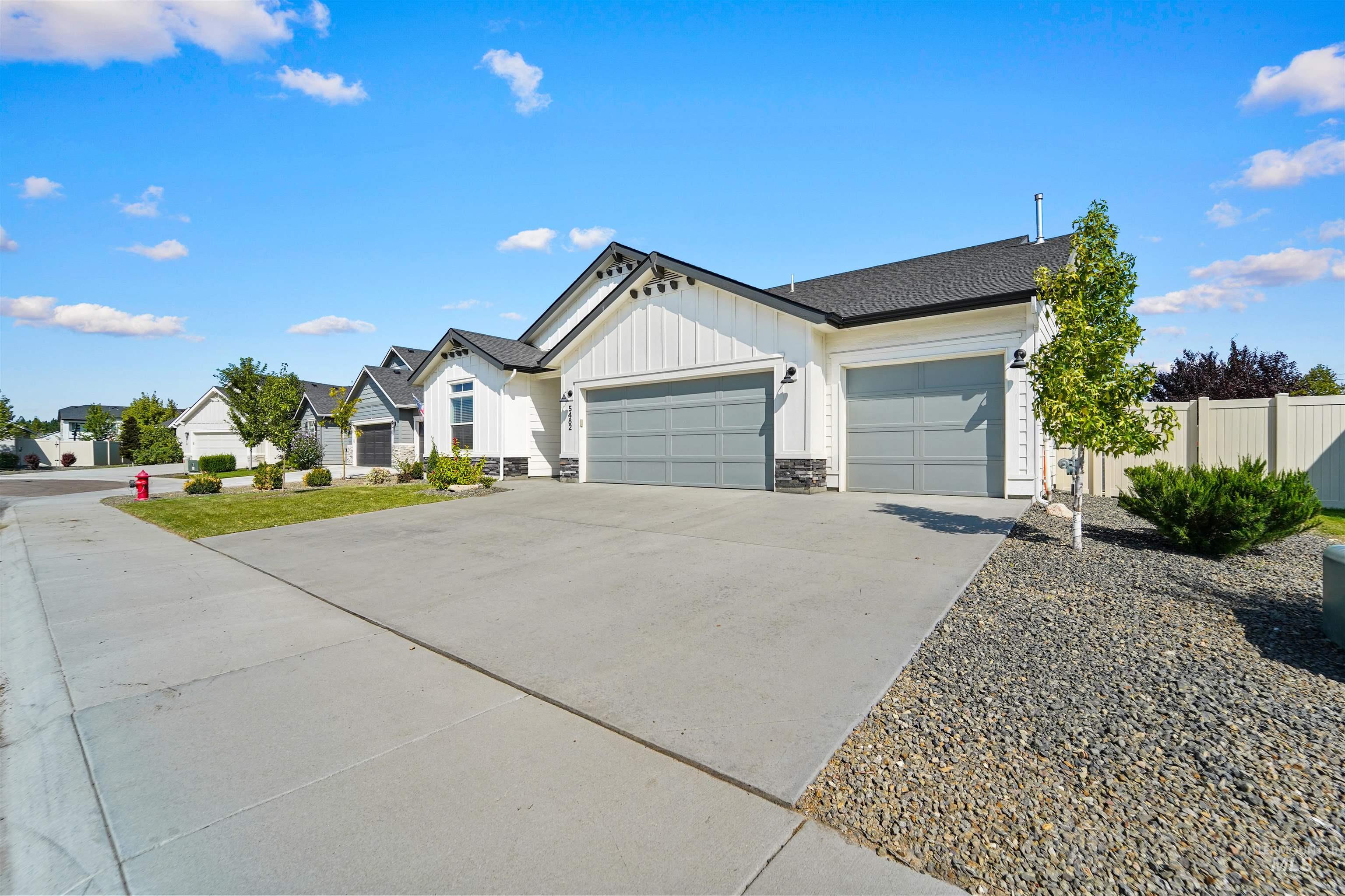 View of front of home with board and batten siding, stone siding, an attached garage, driveway, and a shingled roof