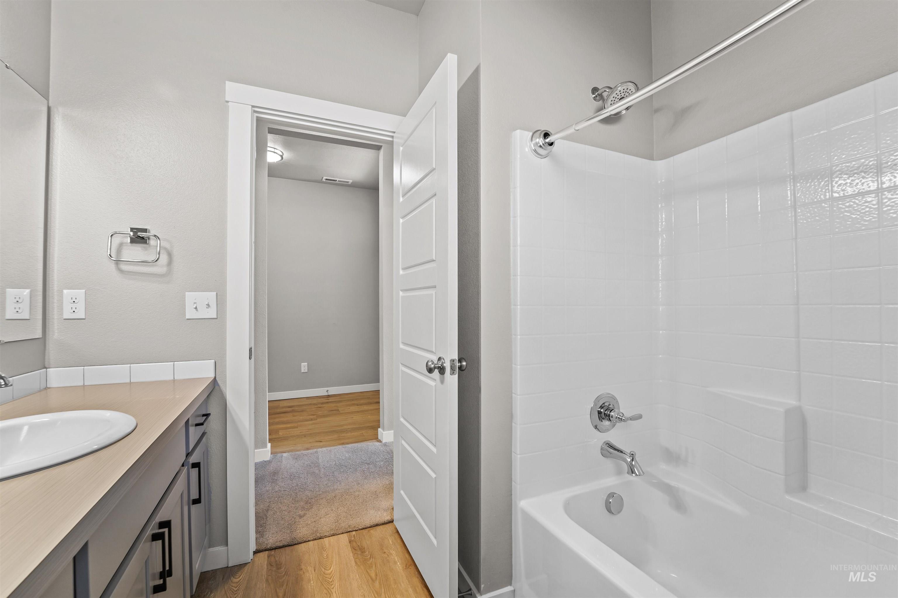 Bathroom featuring light wood-type flooring, bathtub / shower combination, and vanity