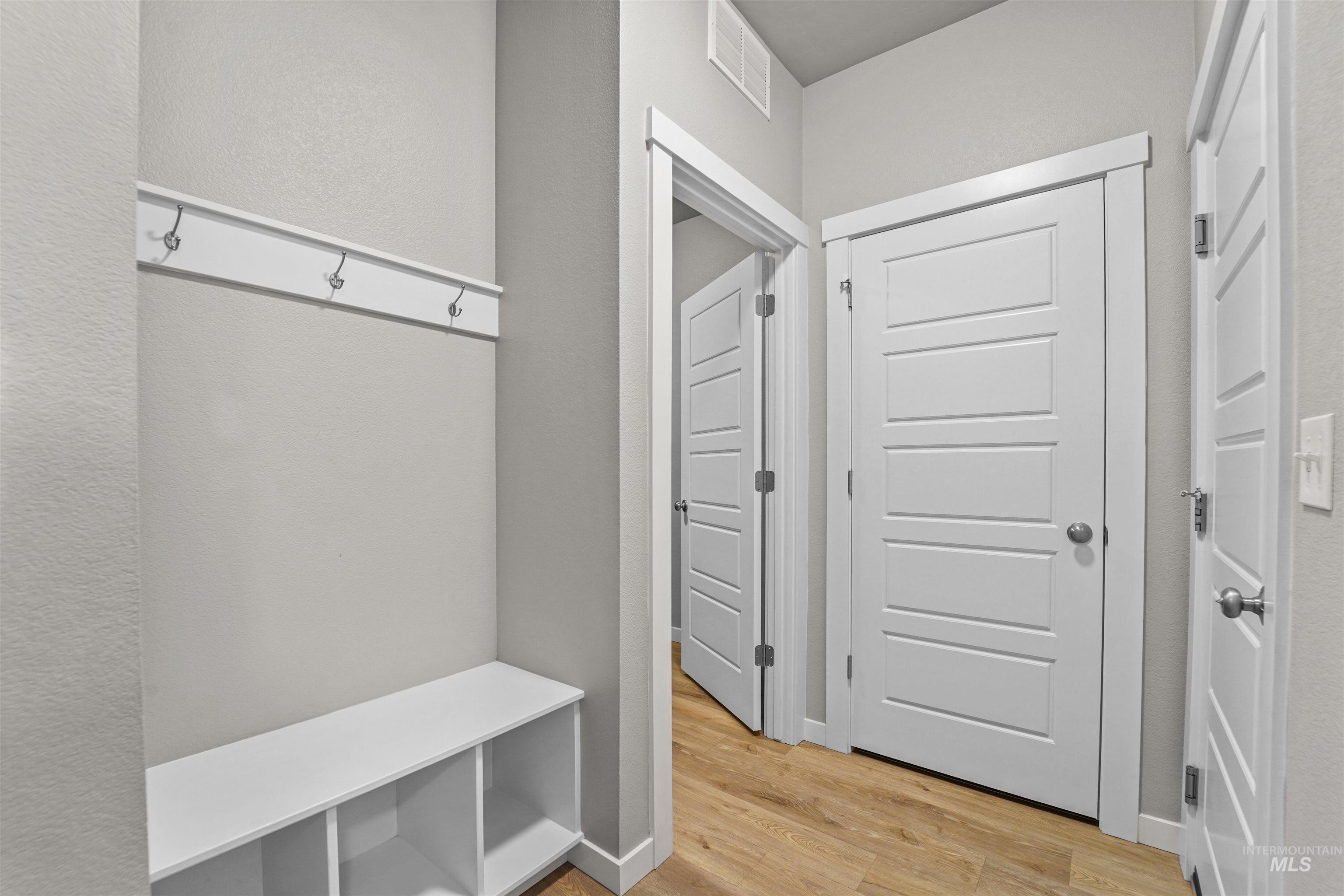 Mudroom with light wood finished floors and a textured wall