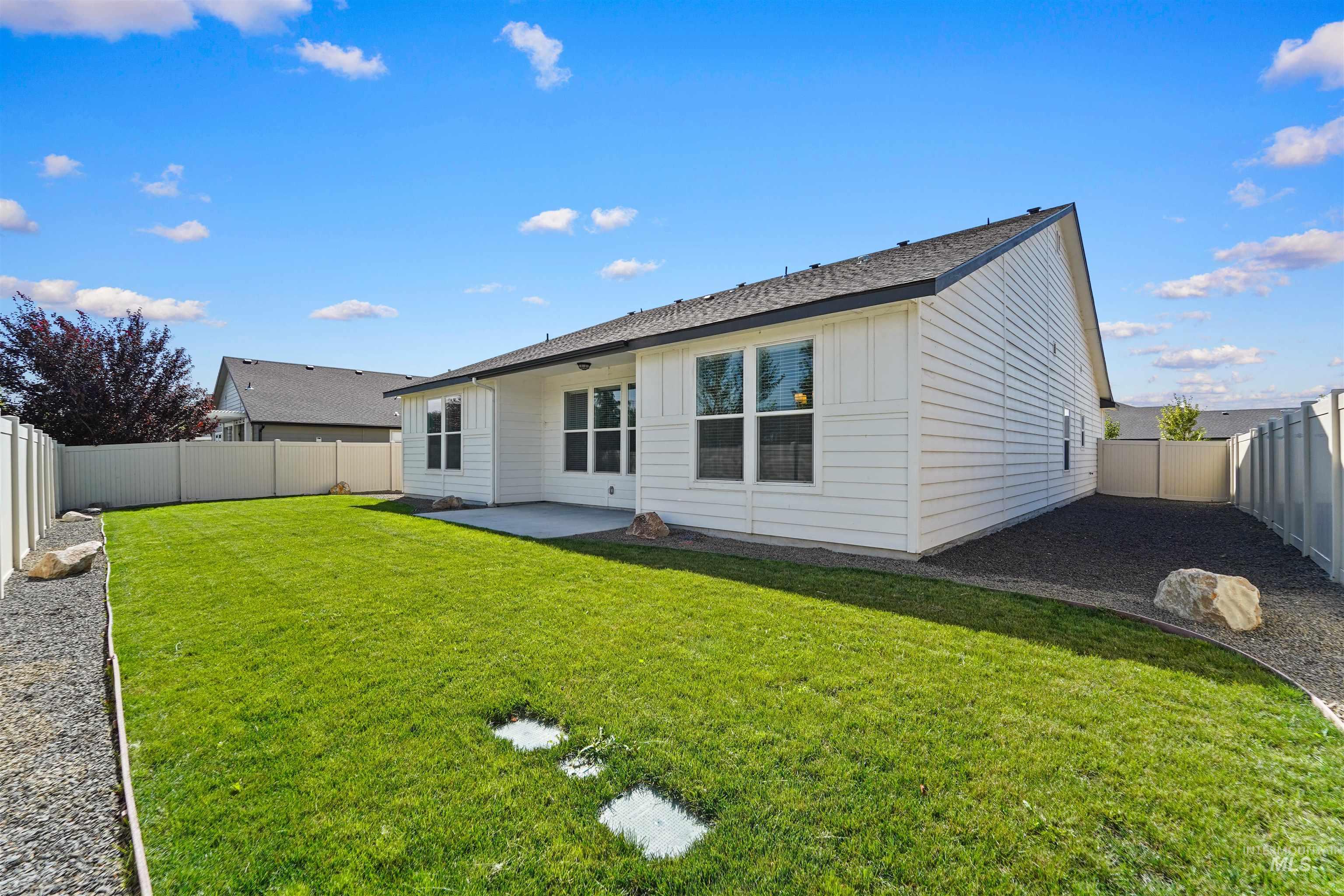 Back of property with a patio area, a fenced backyard, board and batten siding, and roof with shingles