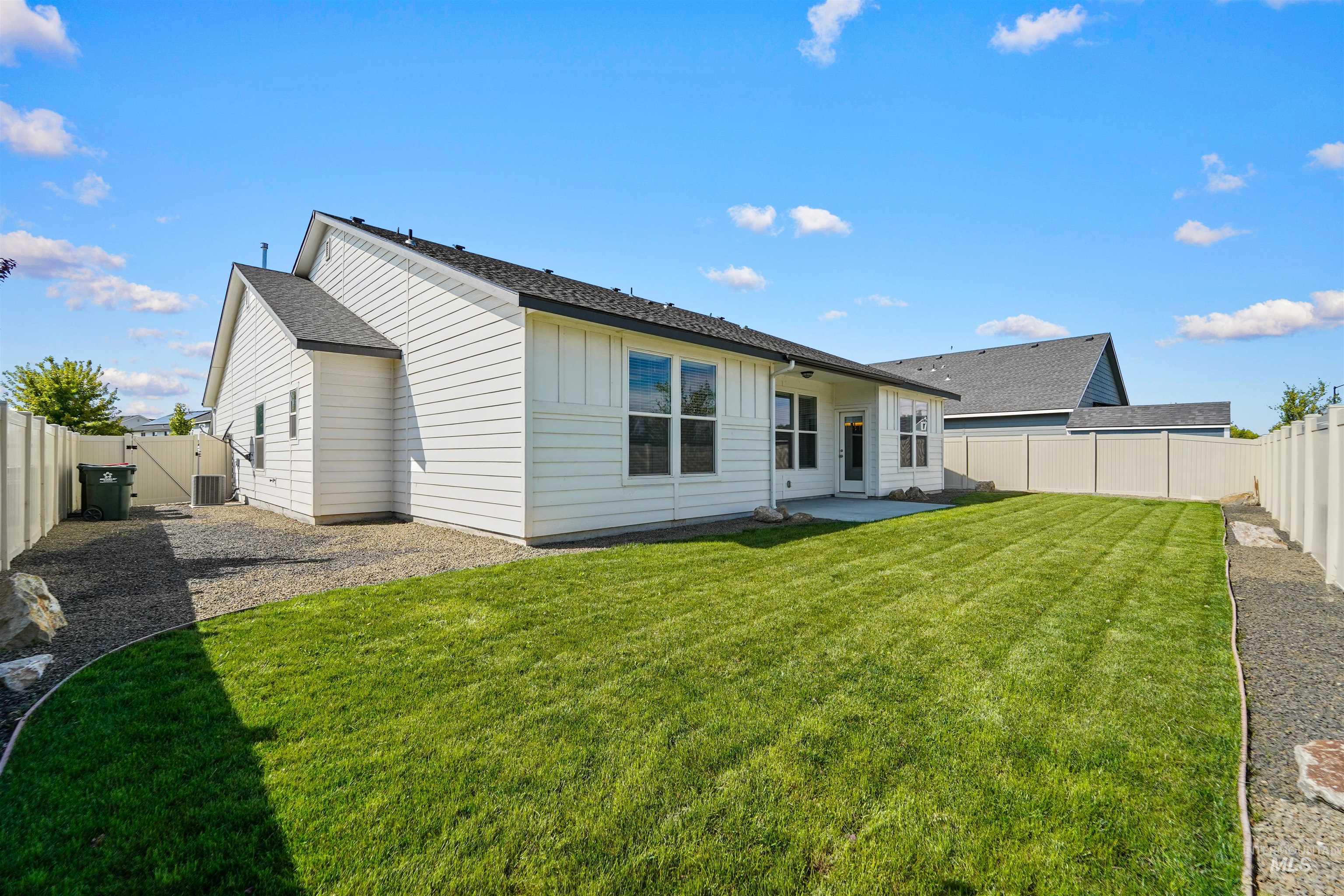 Rear view of house with a fenced backyard, a patio, a gate, board and batten siding, and a shingled roof