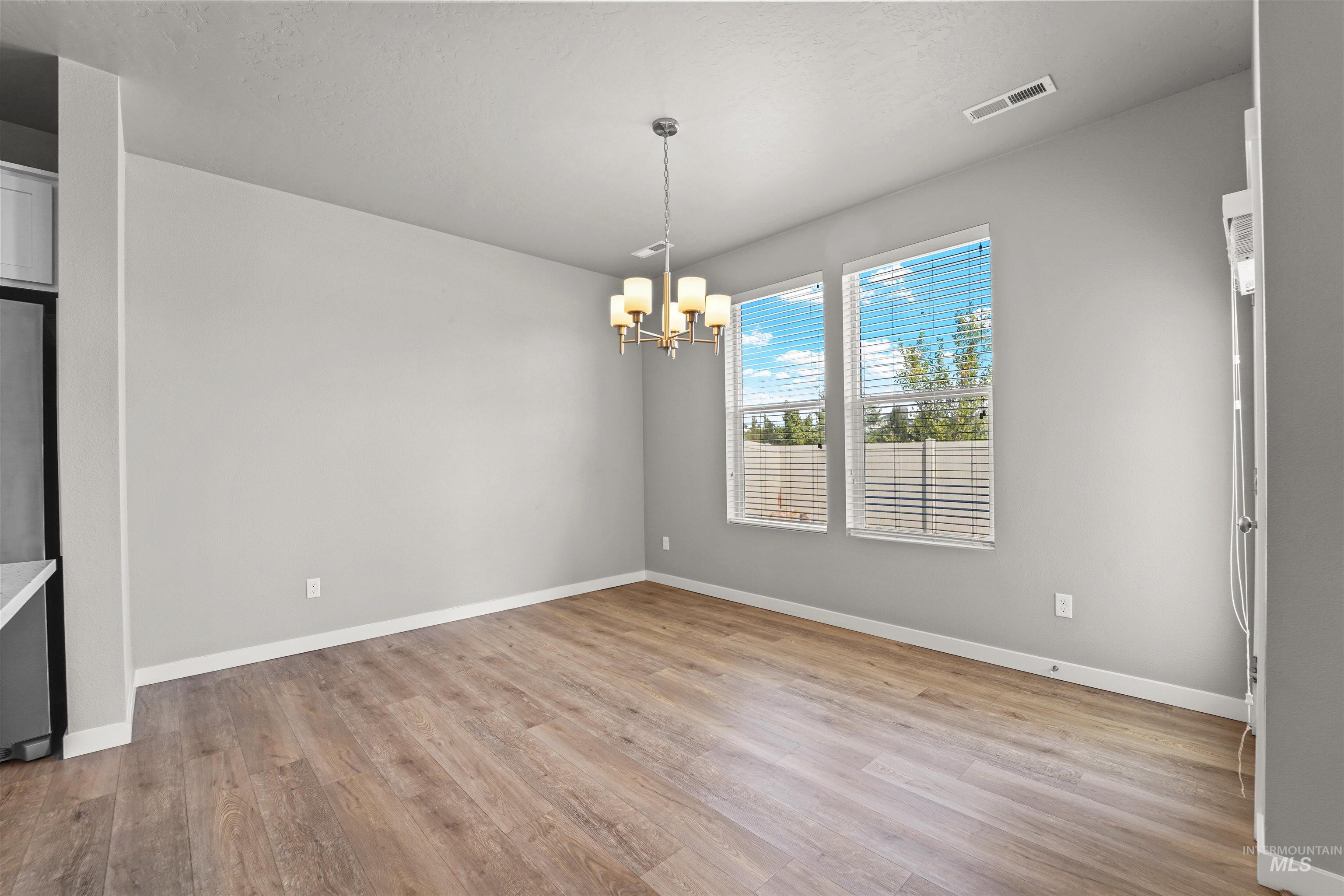 Unfurnished dining area with light wood-style floors, a chandelier, and a textured ceiling