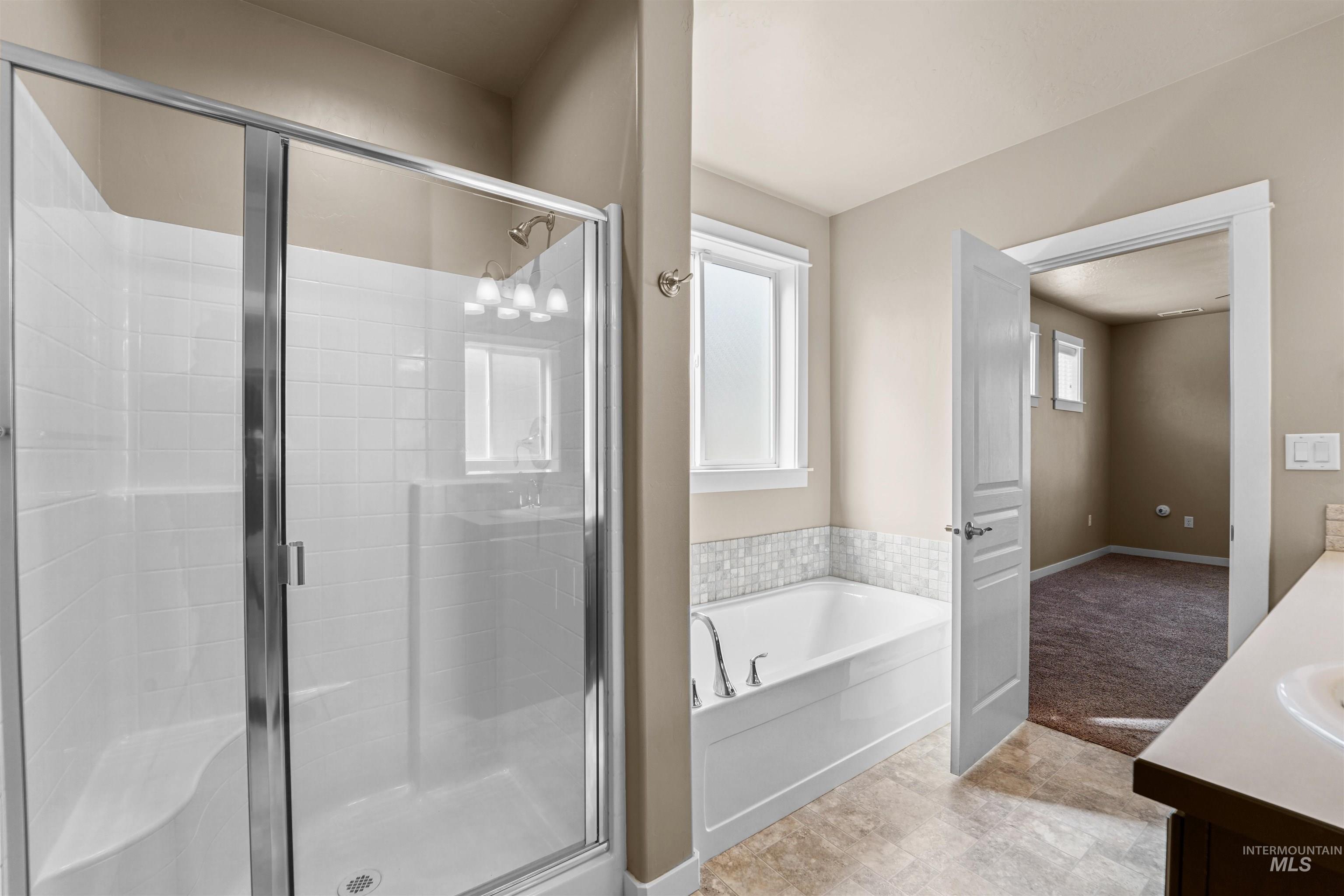 Bathroom featuring a garden tub, a stall shower, and vanity
