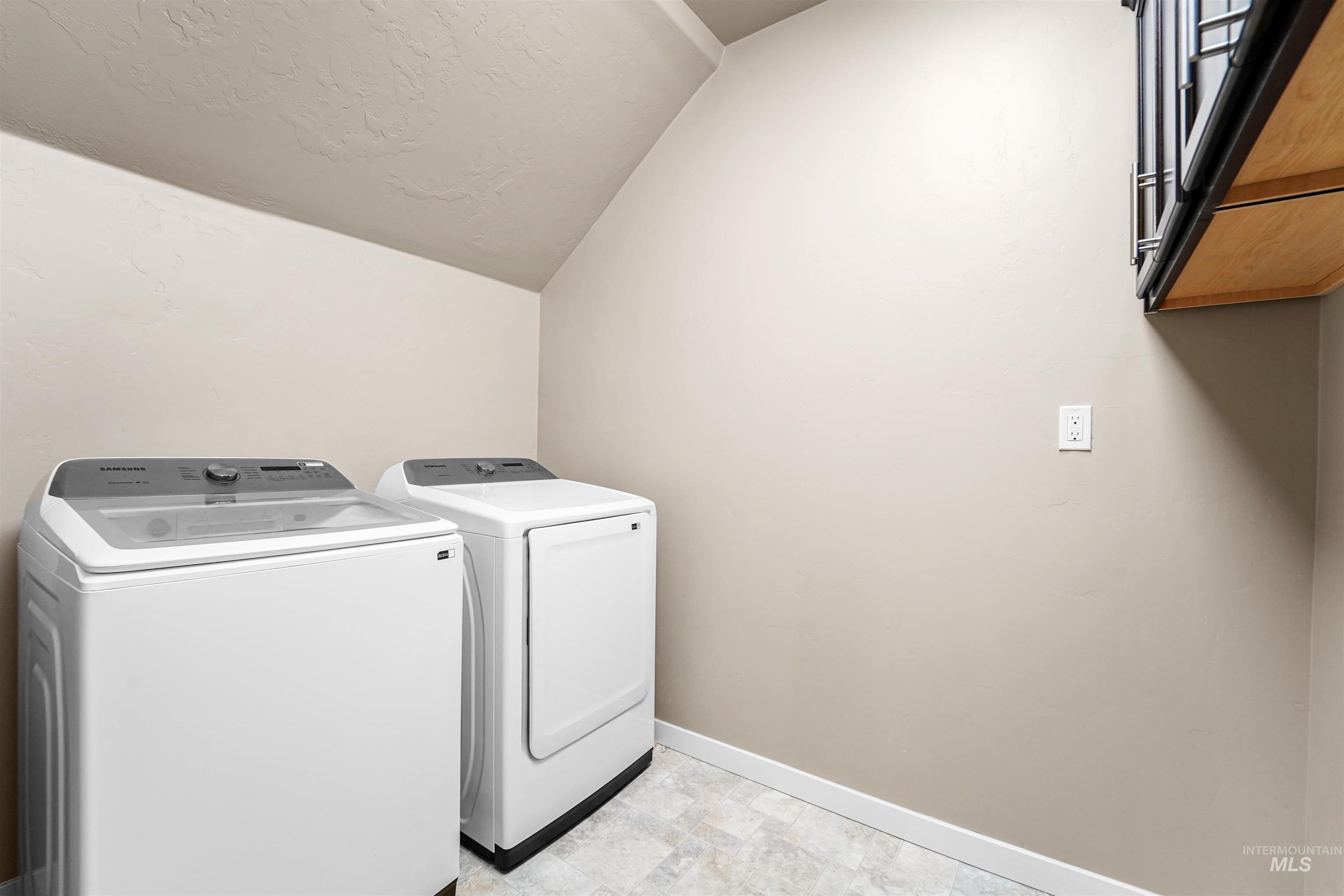 Washroom with washer and clothes dryer and a textured ceiling