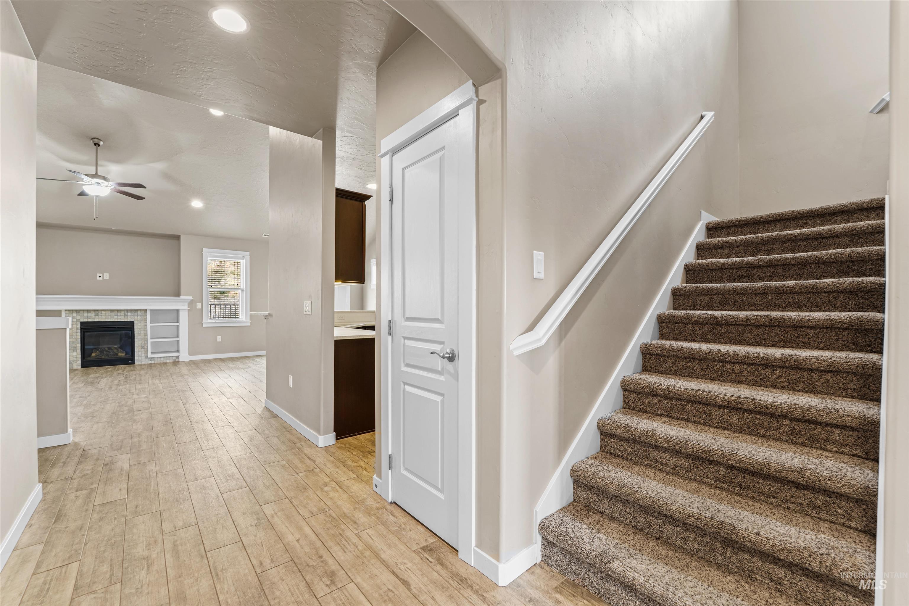 Stairs featuring wood finished floors, a glass covered fireplace, recessed lighting, arched walkways, and ceiling fan