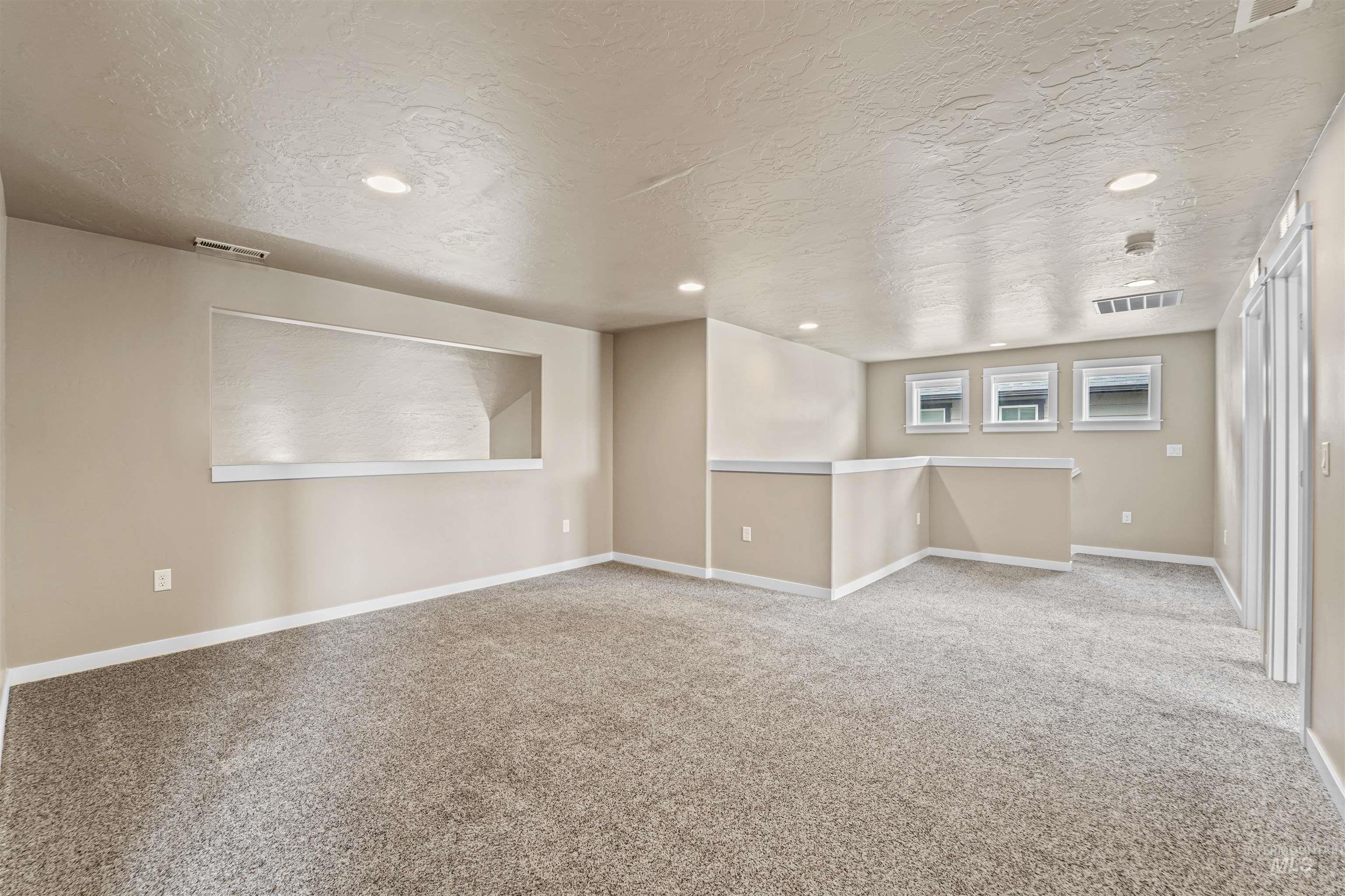 Spare room with carpet, a textured ceiling, and recessed lighting