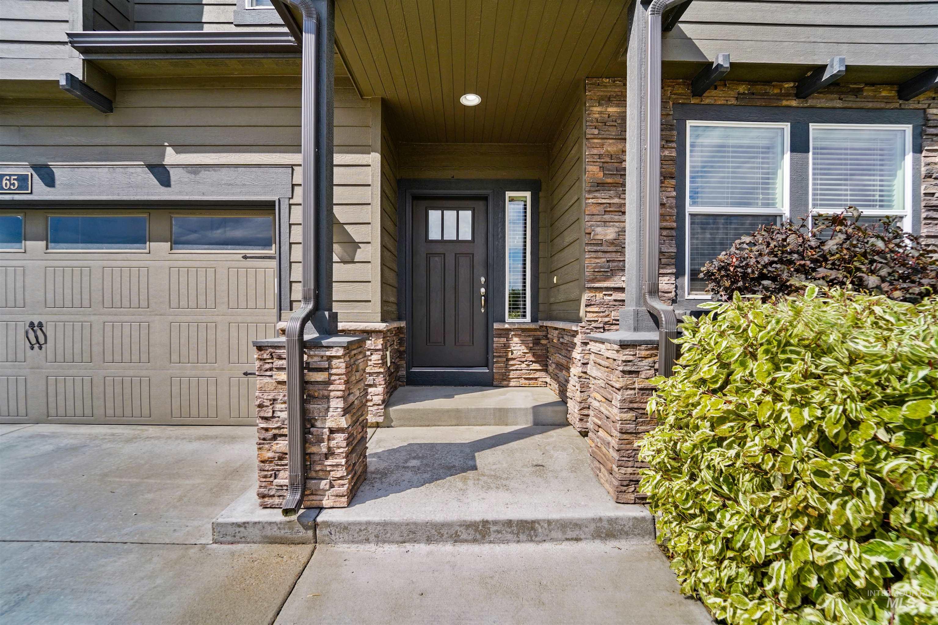 Entrance to property featuring stone siding and a garage