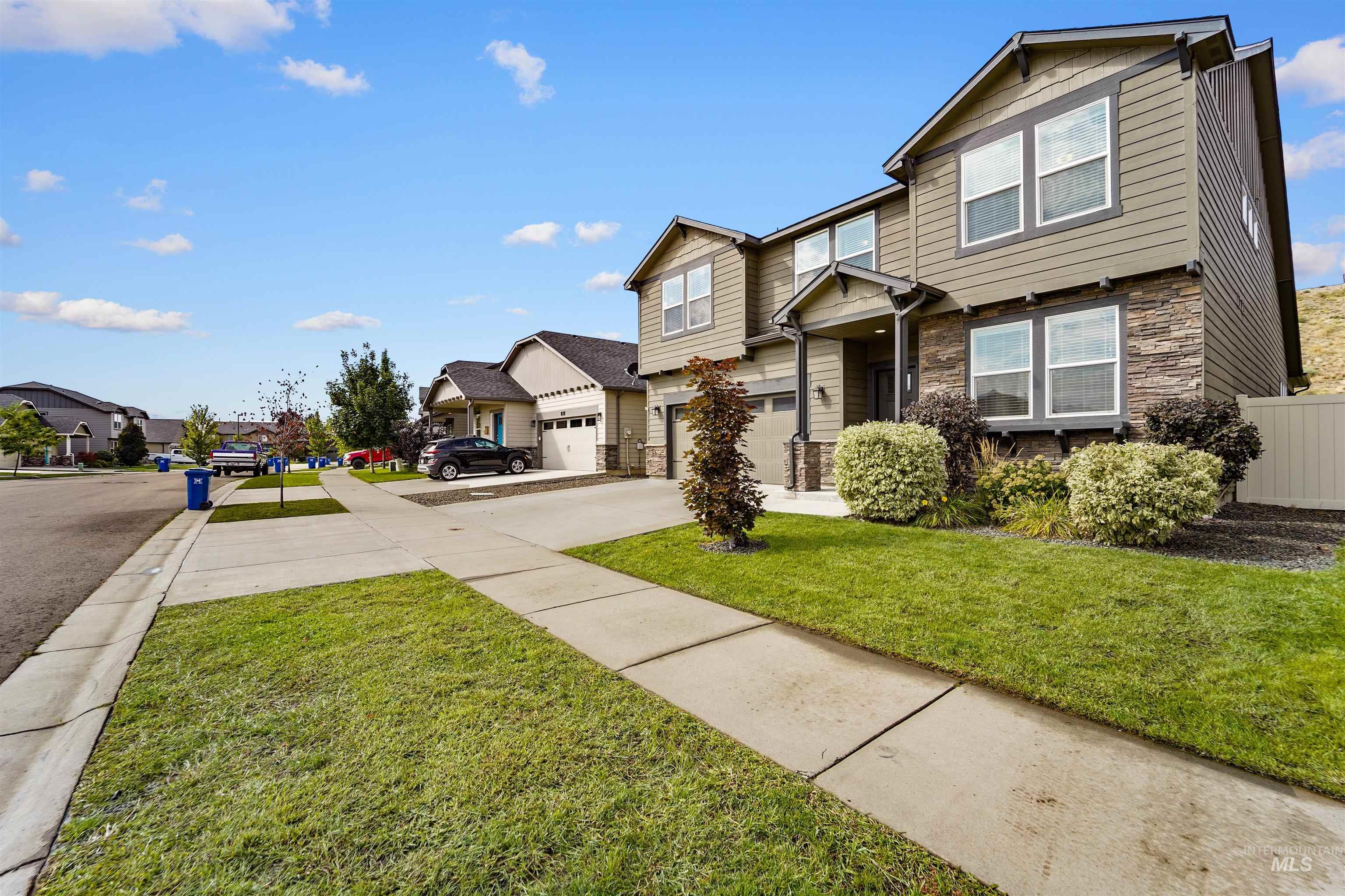 View of front facade with stone siding, concrete driveway, a garage, and a residential view