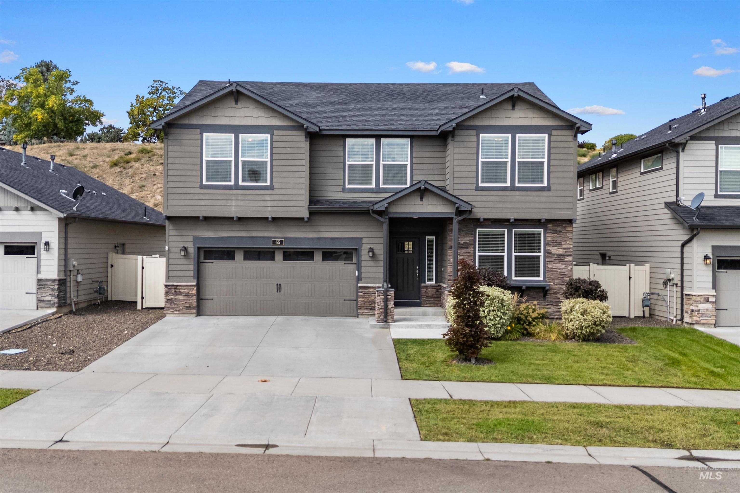 Craftsman-style home featuring stone siding, driveway, roof with shingles, and a garage