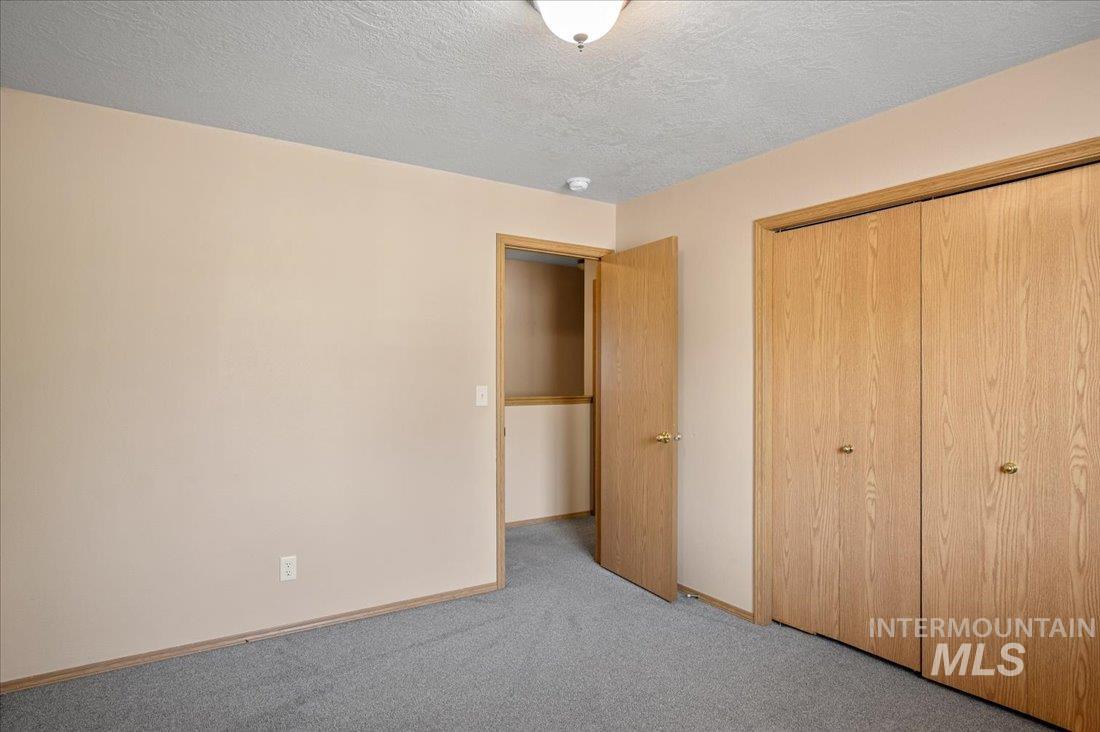 Unfurnished bedroom with a textured ceiling, carpet, and a closet