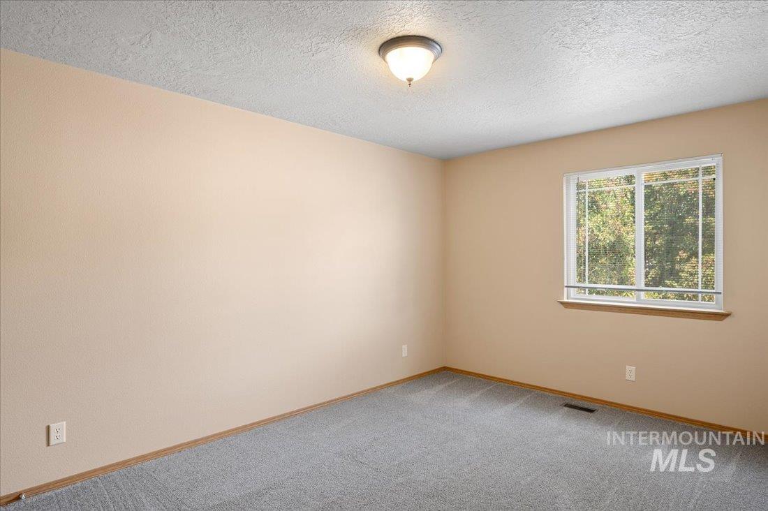 Spare room with a textured ceiling and light carpet