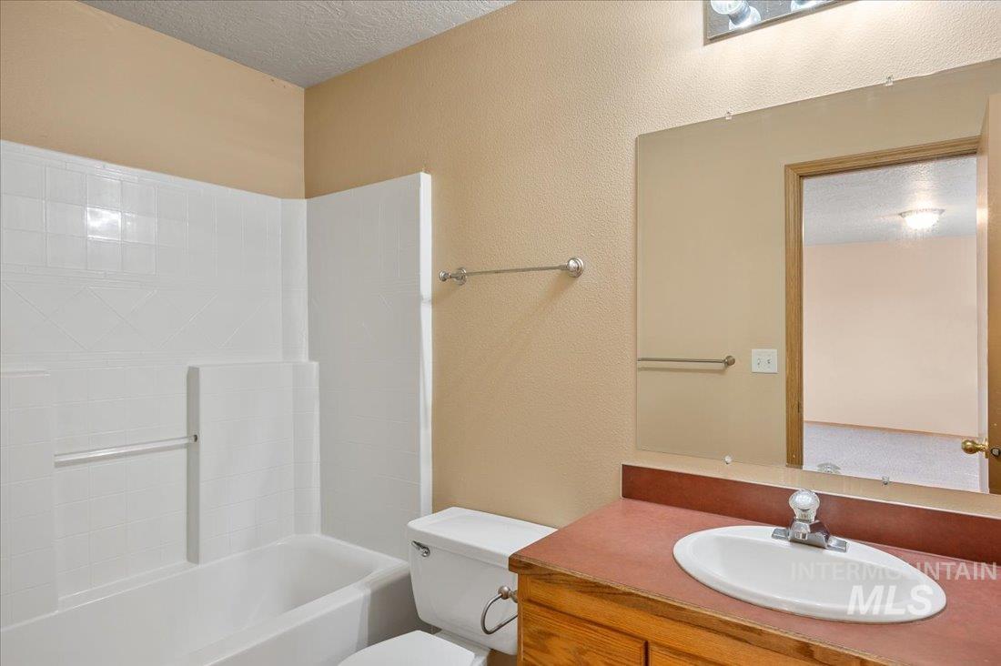 Bathroom featuring a textured ceiling, shower / washtub combination, a textured wall, and vanity