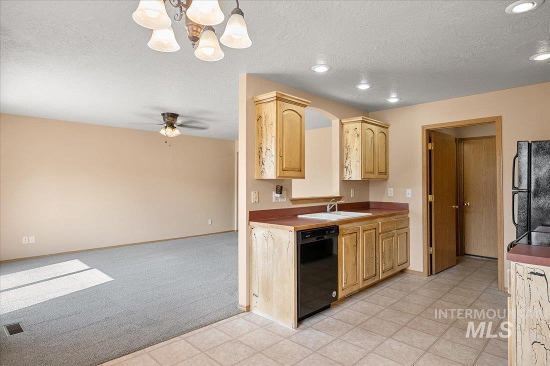 Kitchen with black appliances, a textured ceiling, a chandelier, light colored carpet, and hanging light fixtures