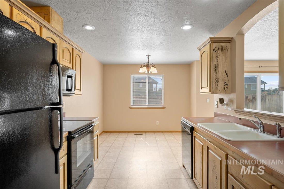 Kitchen featuring black appliances, a textured ceiling, hanging light fixtures, a chandelier, and recessed lighting