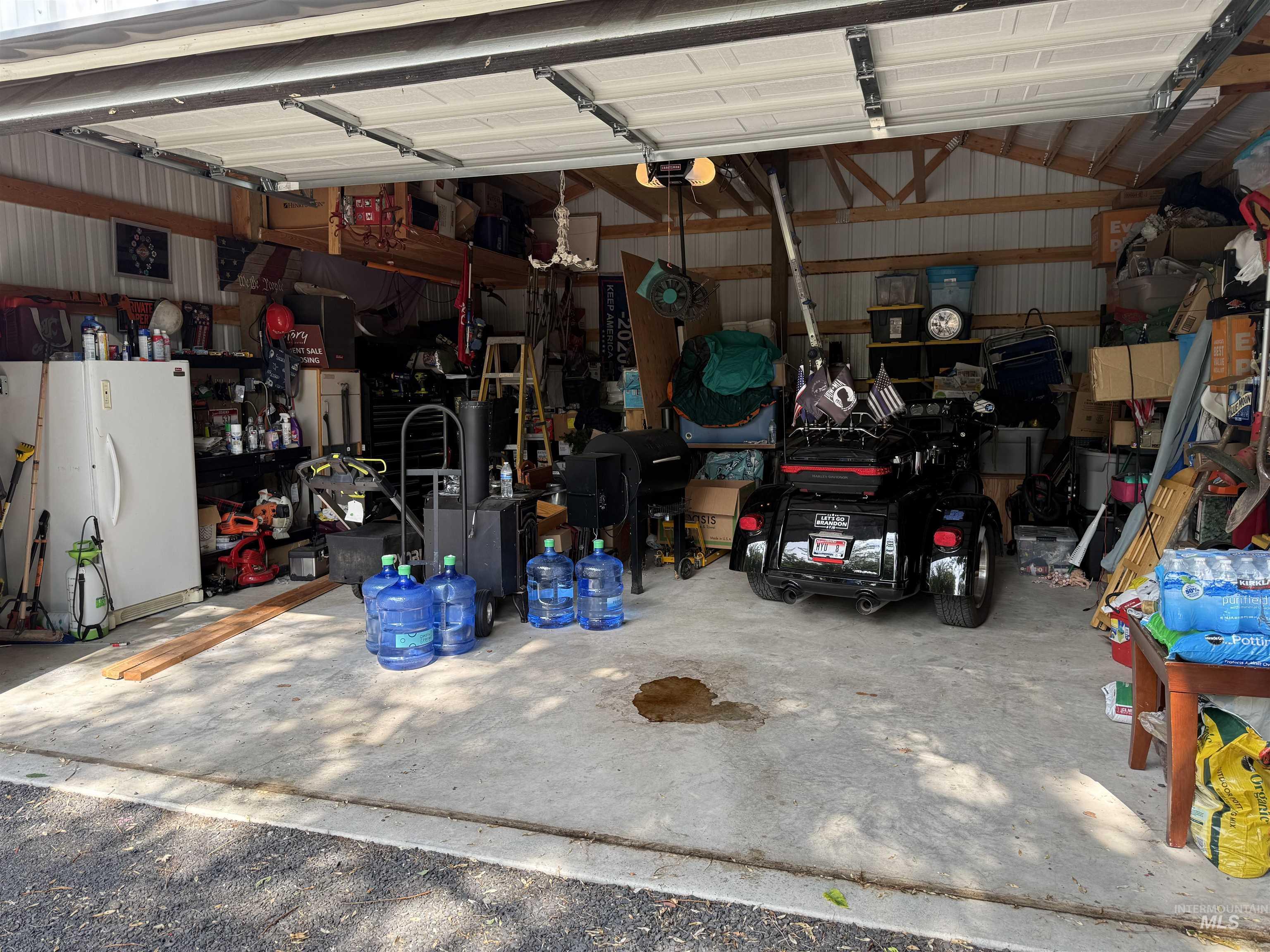 Garage with freestanding refrigerator, metal wall, a garage door opener, and a workshop area
