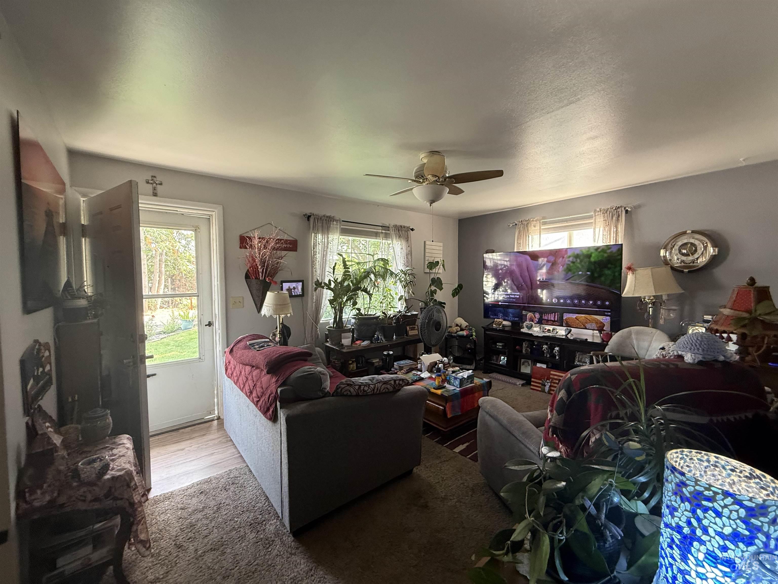Living room with plenty of natural light, wood finished floors, and a ceiling fan