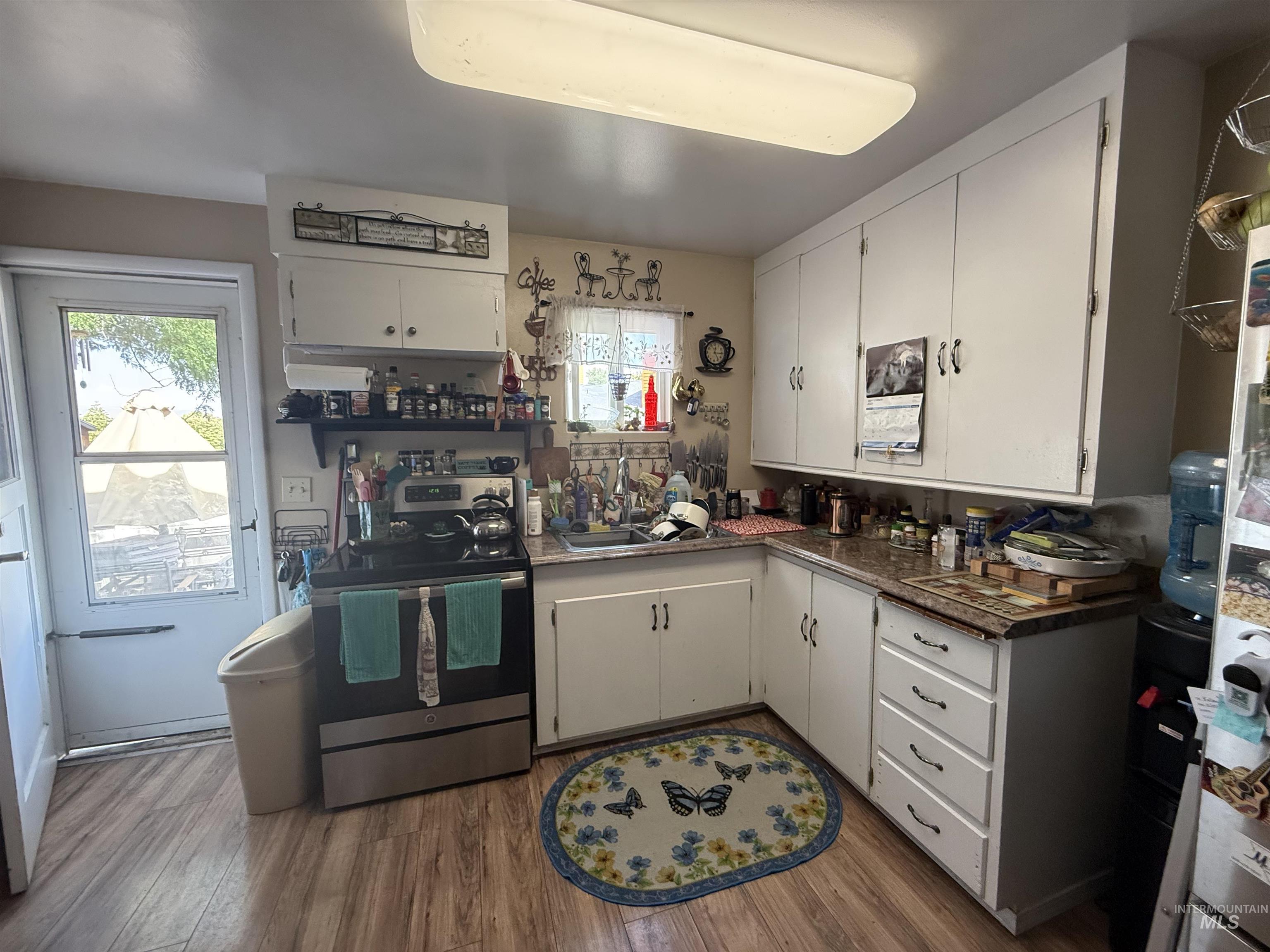 Kitchen featuring dark countertops, electric range, white cabinetry, dark wood-style flooring, and healthy amount of natural light