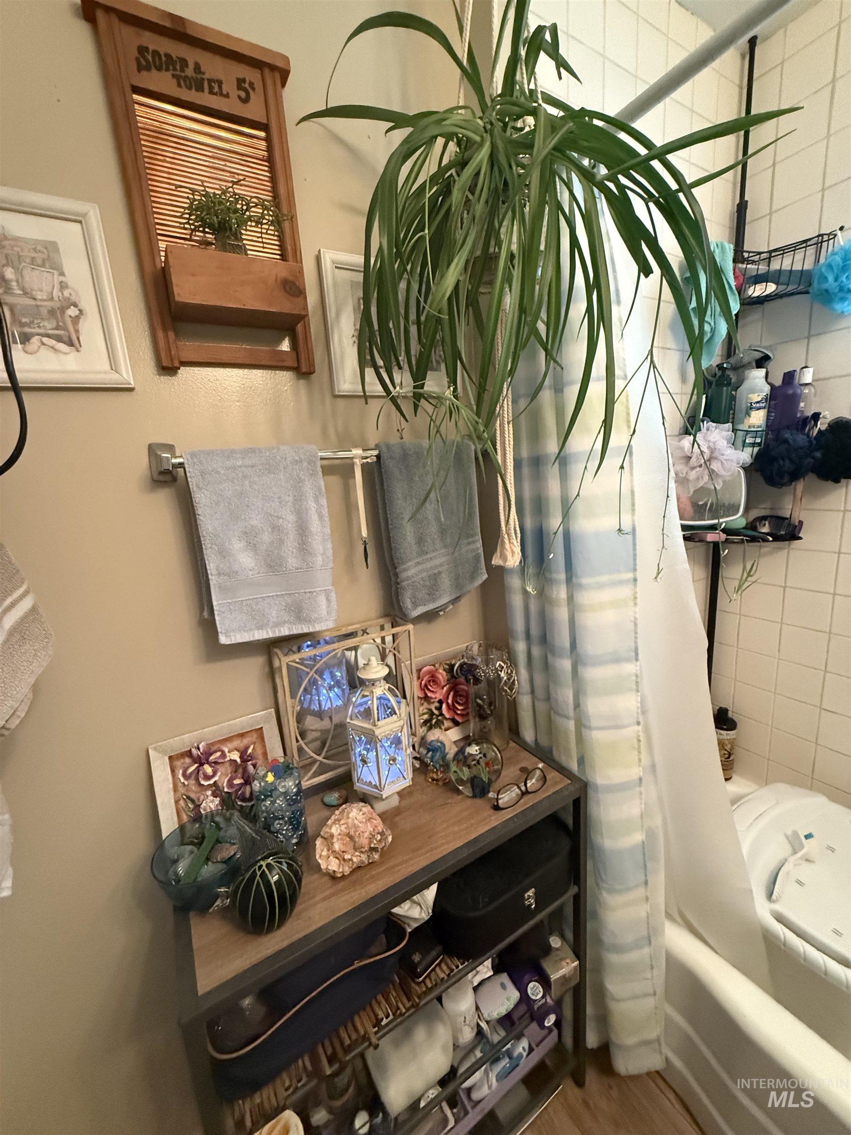 Bathroom view of wood finished floors and shower / bath combo