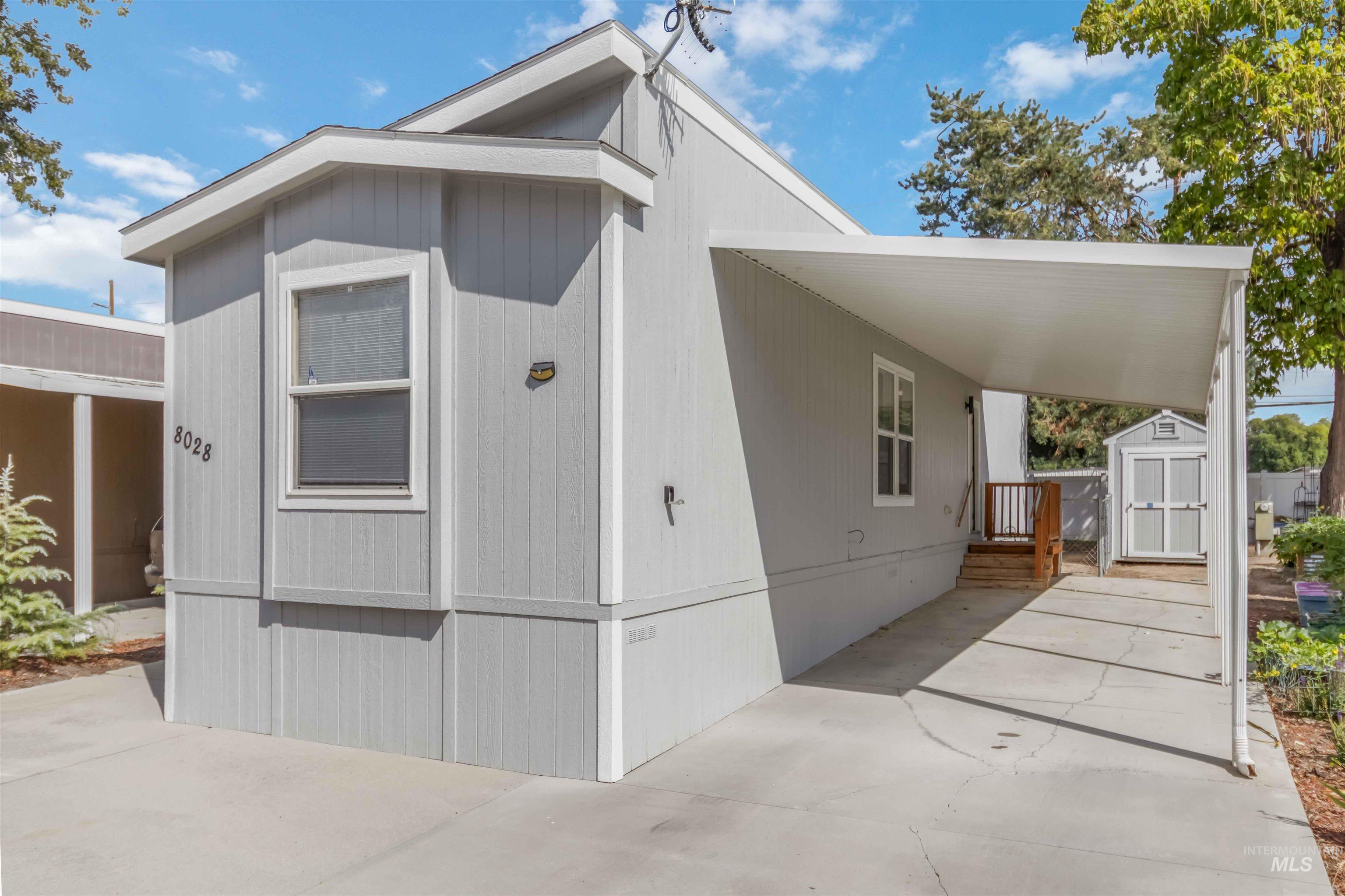 View of front of house featuring a storage unit, a carport, and driveway