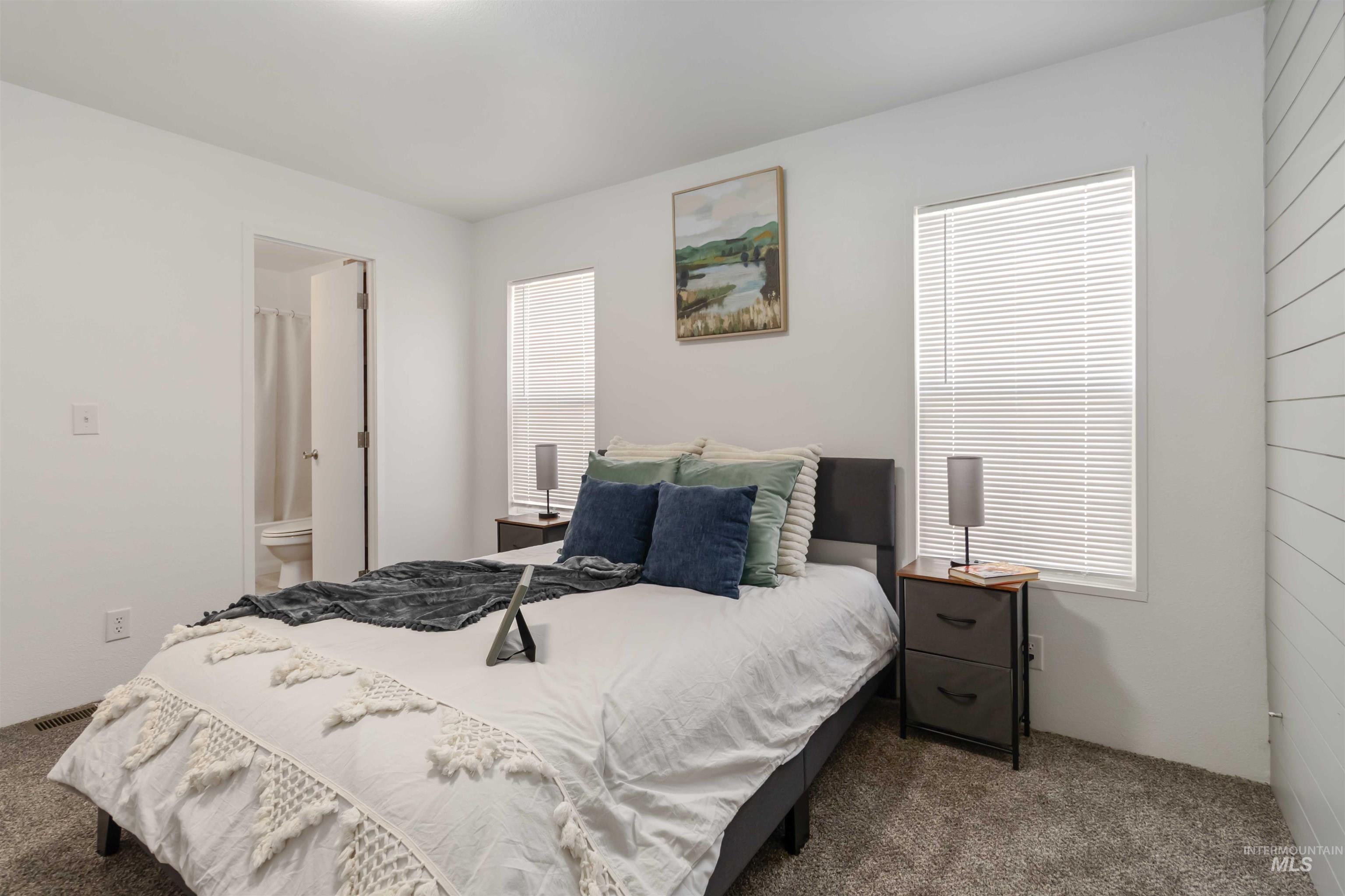 Bedroom with carpet floors, multiple windows, and ensuite bathroom