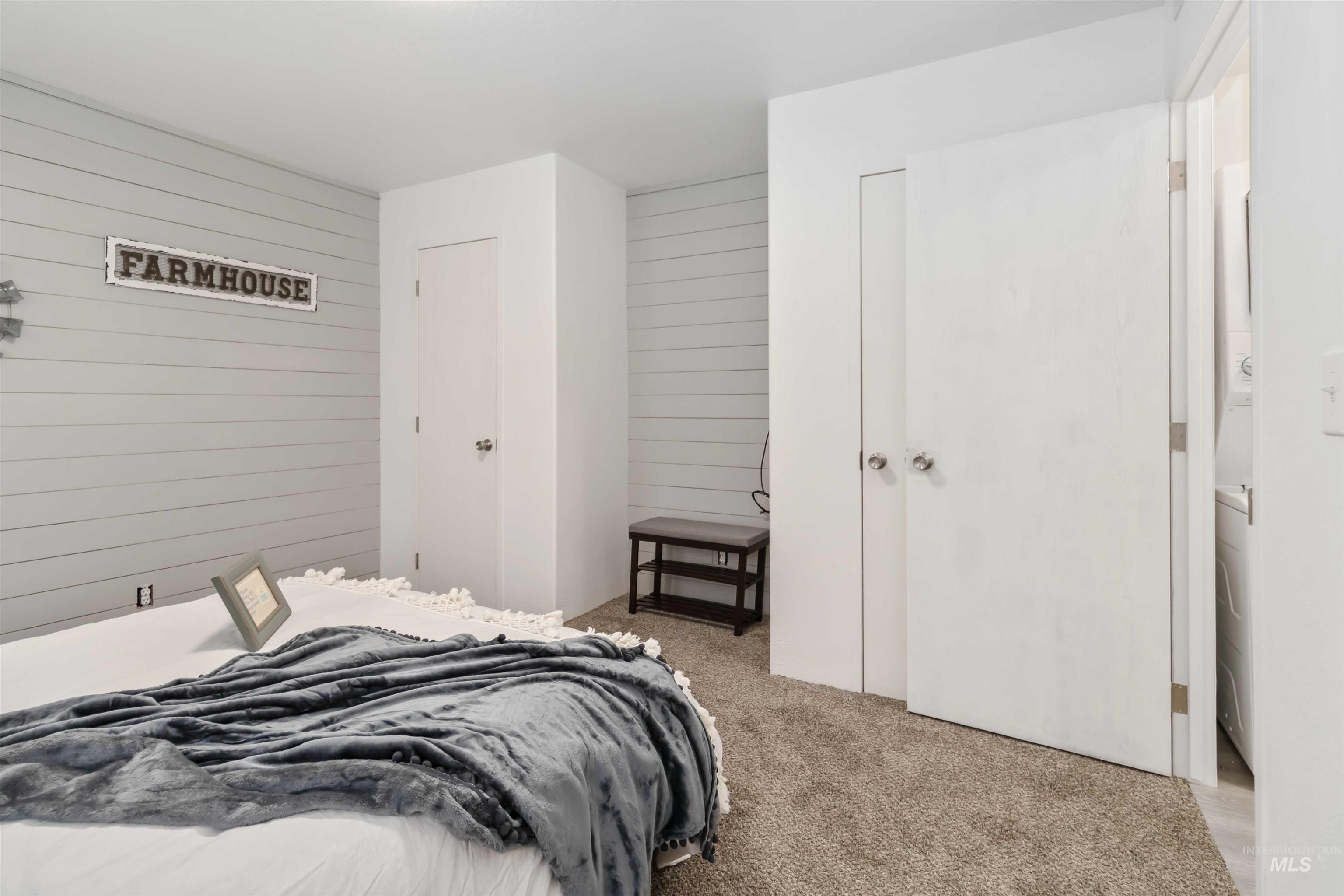 Bedroom with wood walls, light carpet, and washer / dryer