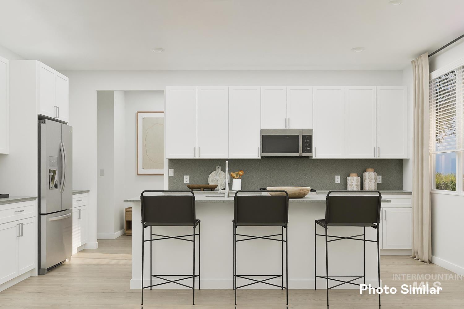 Kitchen featuring an island with sink, tasteful backsplash, appliances with stainless steel finishes, white cabinets, and light wood-type flooring