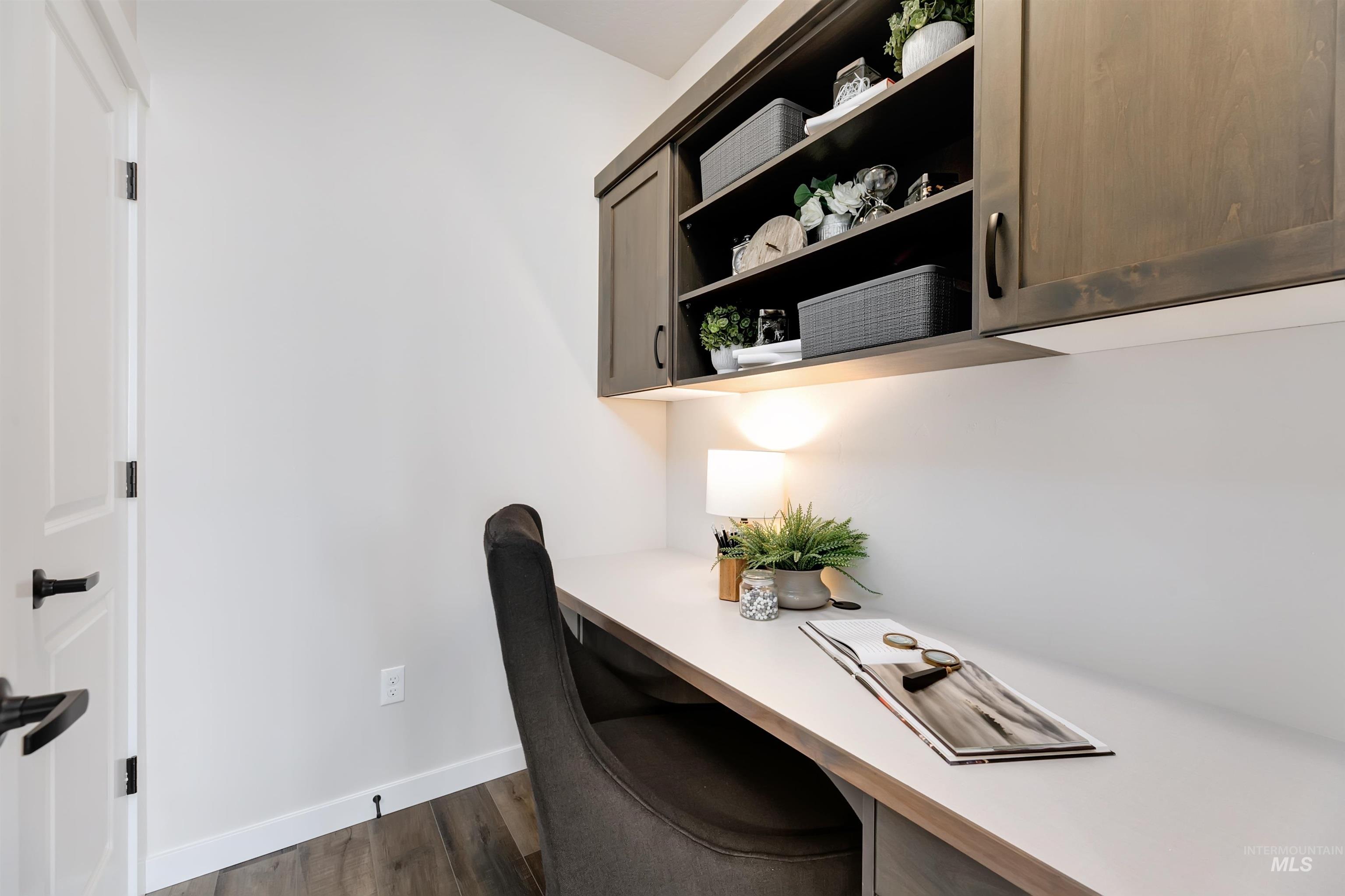 Home office with built in study area and dark wood-type flooring