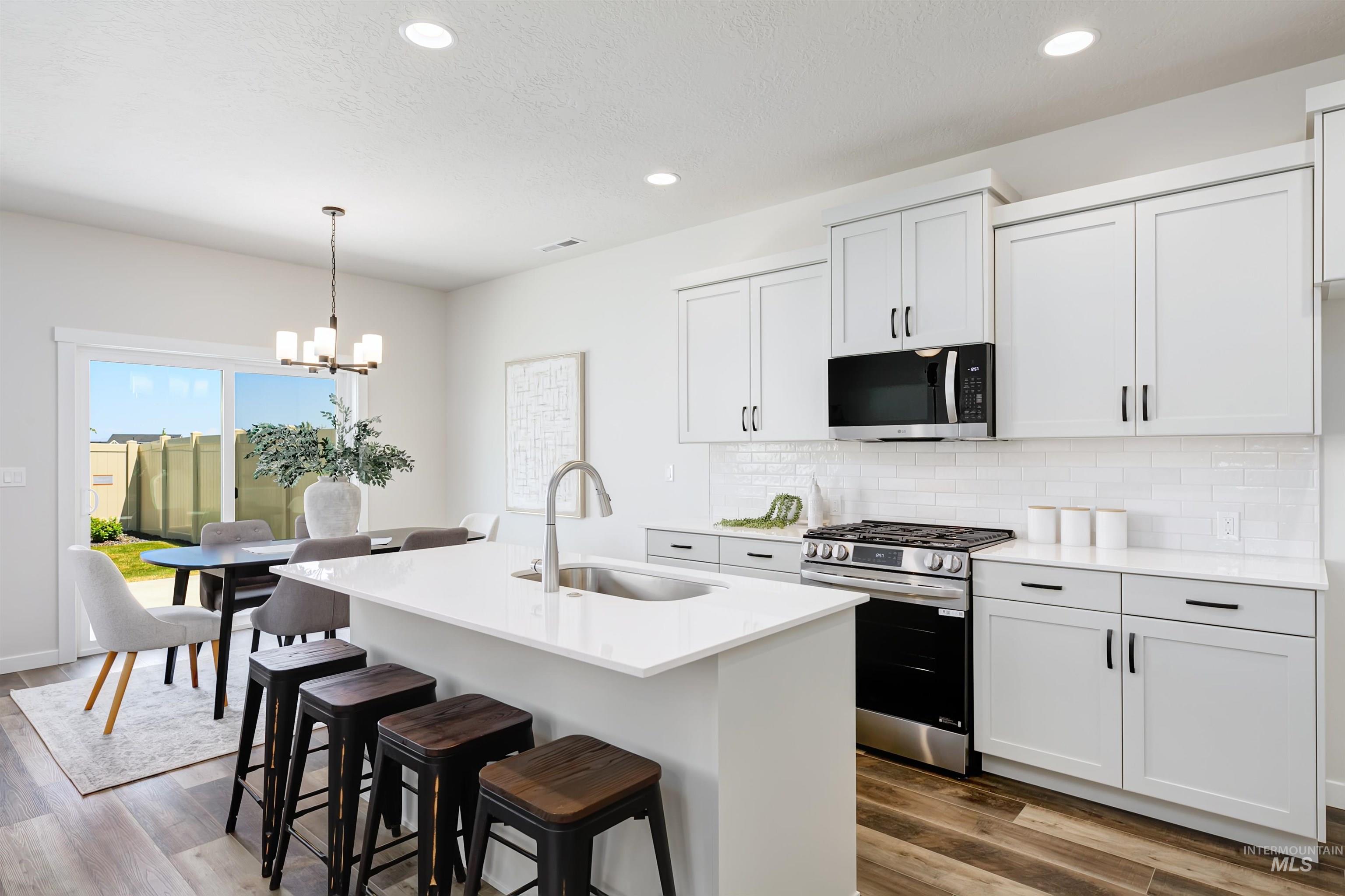 Kitchen featuring stainless steel appliances, decorative backsplash, wood finished floors, a chandelier, and recessed lighting