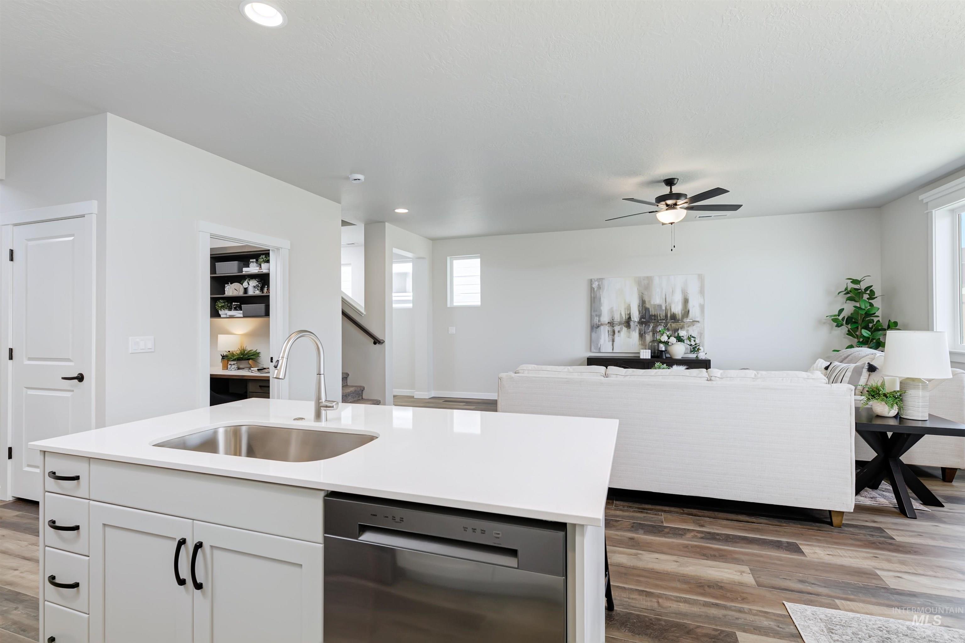 Kitchen with dishwasher, open floor plan, wood finished floors, white cabinetry, and recessed lighting