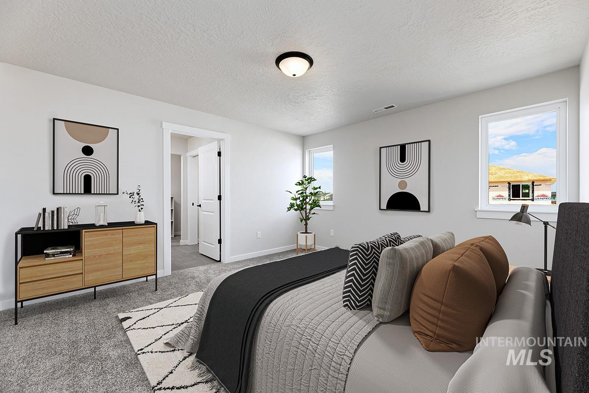 Carpeted bedroom featuring a textured ceiling and baseboards
