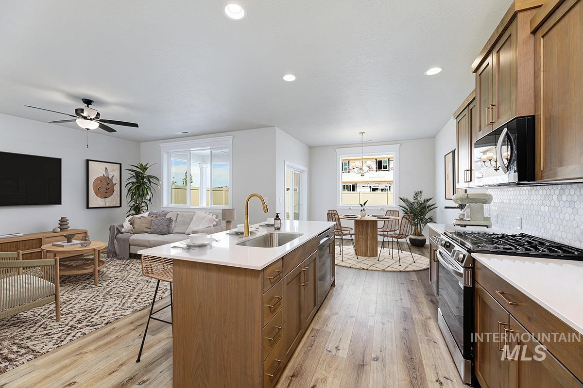 Kitchen featuring appliances with stainless steel finishes, light wood-type flooring, backsplash, brown cabinetry, and recessed lighting