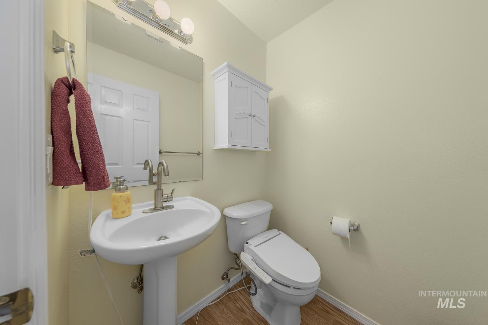 Half bathroom with toilet and wood finished floors